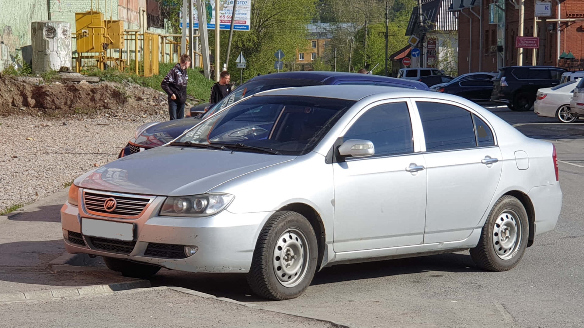  壁紙 — 一輛銀色房車停泊在陽光明媚的城市街道上，背景有行人和其他車輛。