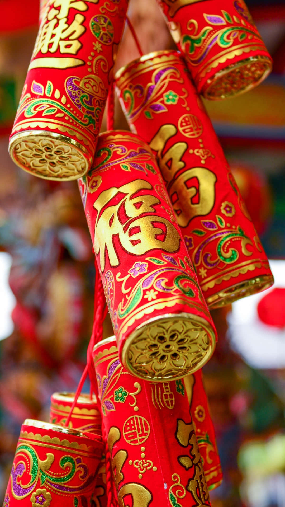  壁紙 — 鮮紅色嘅爆竹，上面有金色中文字同精緻嘅花卉圖案，掛成一個喜慶嘅簇。