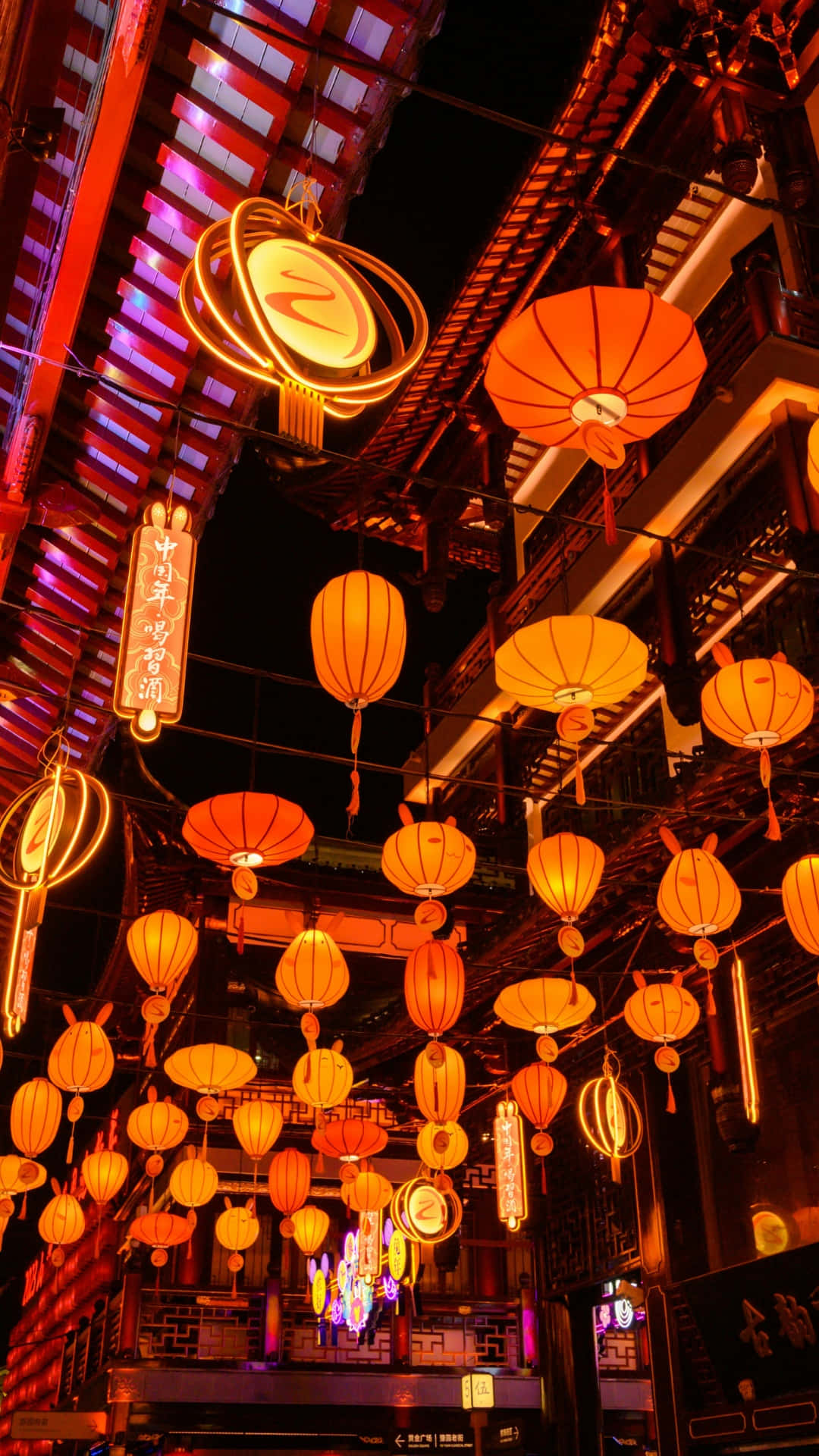  壁紙 — 鮮豔的橙色燈籠在夜間繁華的傳統中式小巷中，對著深色木樑溫暖地發光。