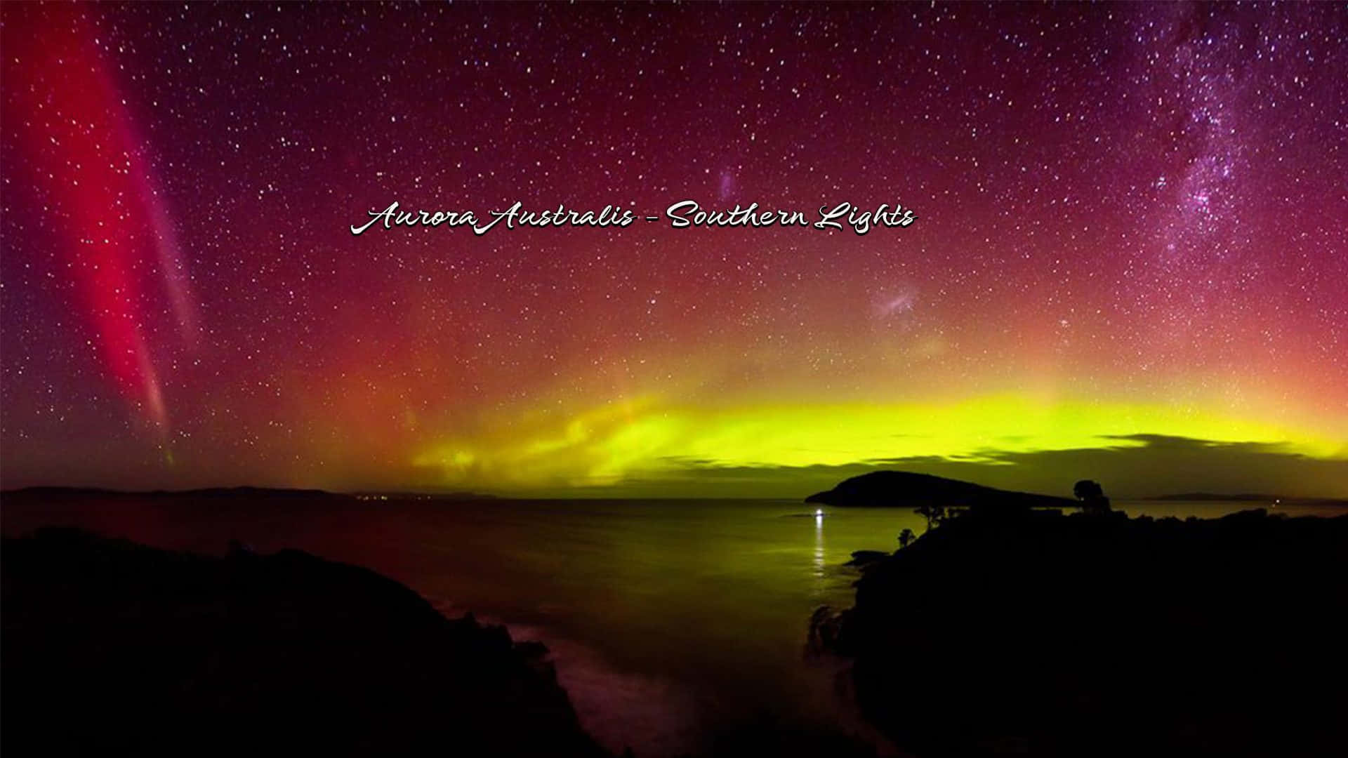  壁紙 — 鮮豔的紅色和黃色南極光在黑暗海岸景觀上方的星空夜空中舞動。