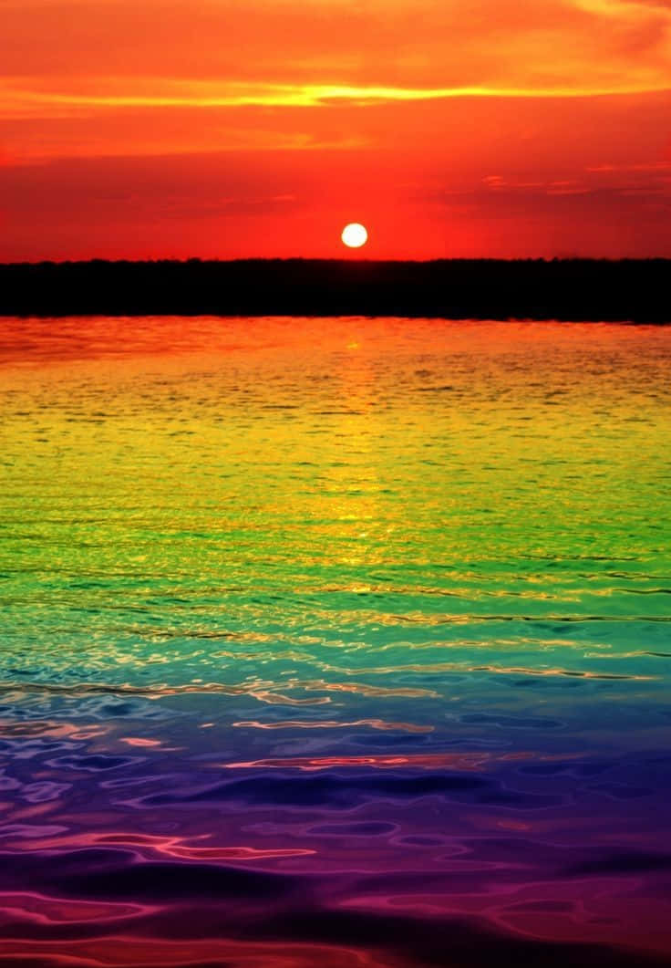 Colorful Sunset 桌布 壁紙 — 鮮豔的夕陽將天空和水面塗成從橙色到紫色的生動彩虹漸變。