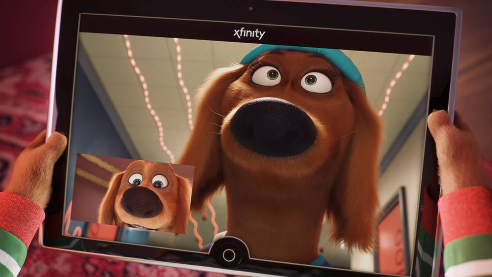 《Sing 2》中的達克斯胡犬安吉 壁紙 — 一個人手持平板電腦，顯示一隻動畫狗與另一隻戴著藍色頭帶的狗進行視像通話。