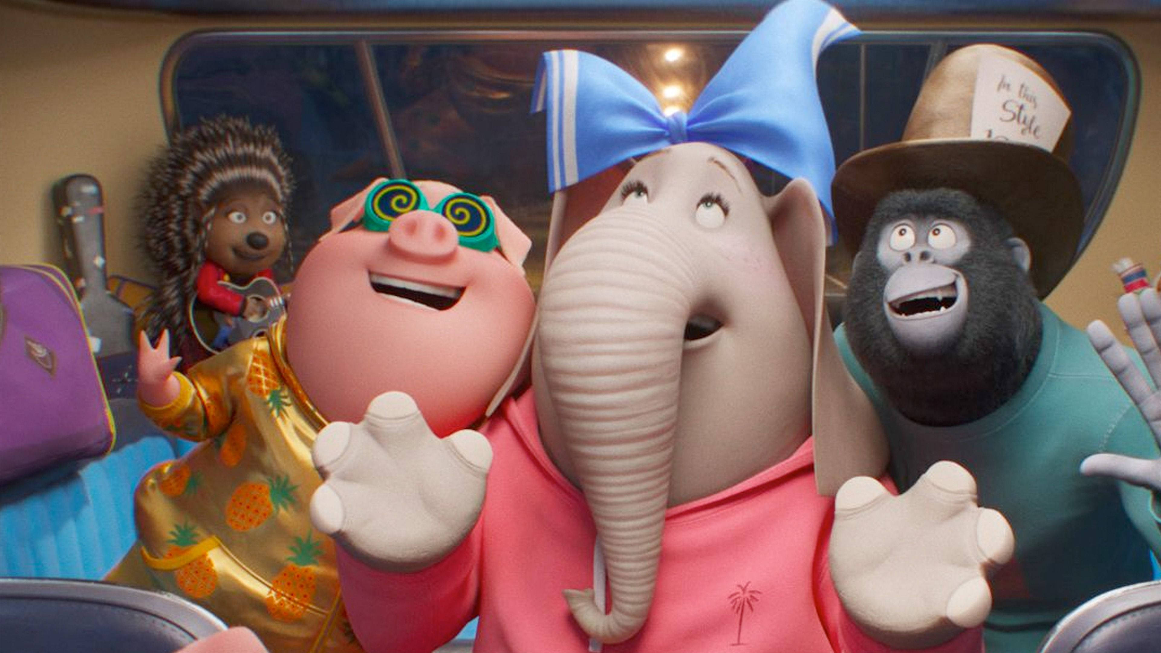 《Sing 2》古尼、米娜與強尼 壁紙 — 四個動畫動物朋友在巴士內愉快地擺姿勢，穿著色彩繽紛的服裝，表情豐富。
