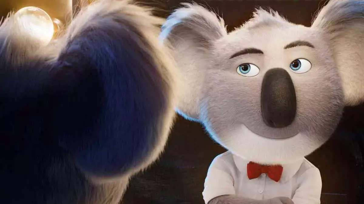 《Sing 2》布斯特·月對鏡 壁紙 — 一隻迷人的動畫樹熊穿著白襯衫和紅色蝴蝶結，用大大的藍眼睛凝視著溫暖金色光芒中模糊的毛茸茸夥伴。