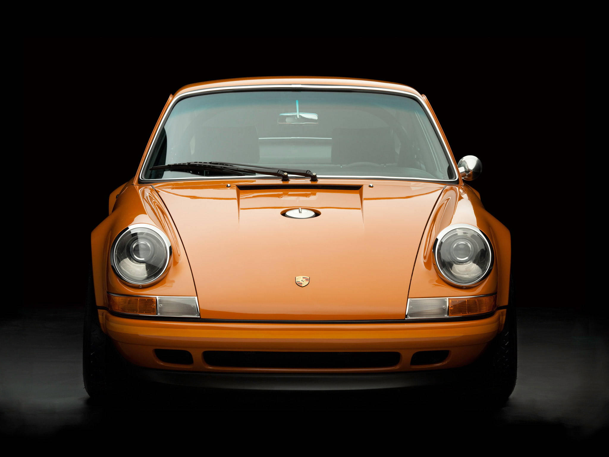 橙色Singer Porsche前引擎蓋 壁紙 — 一輛充滿活力的橙色經典保時捷911正面視圖，在攝影棚燈光下於純黑背景中閃耀。