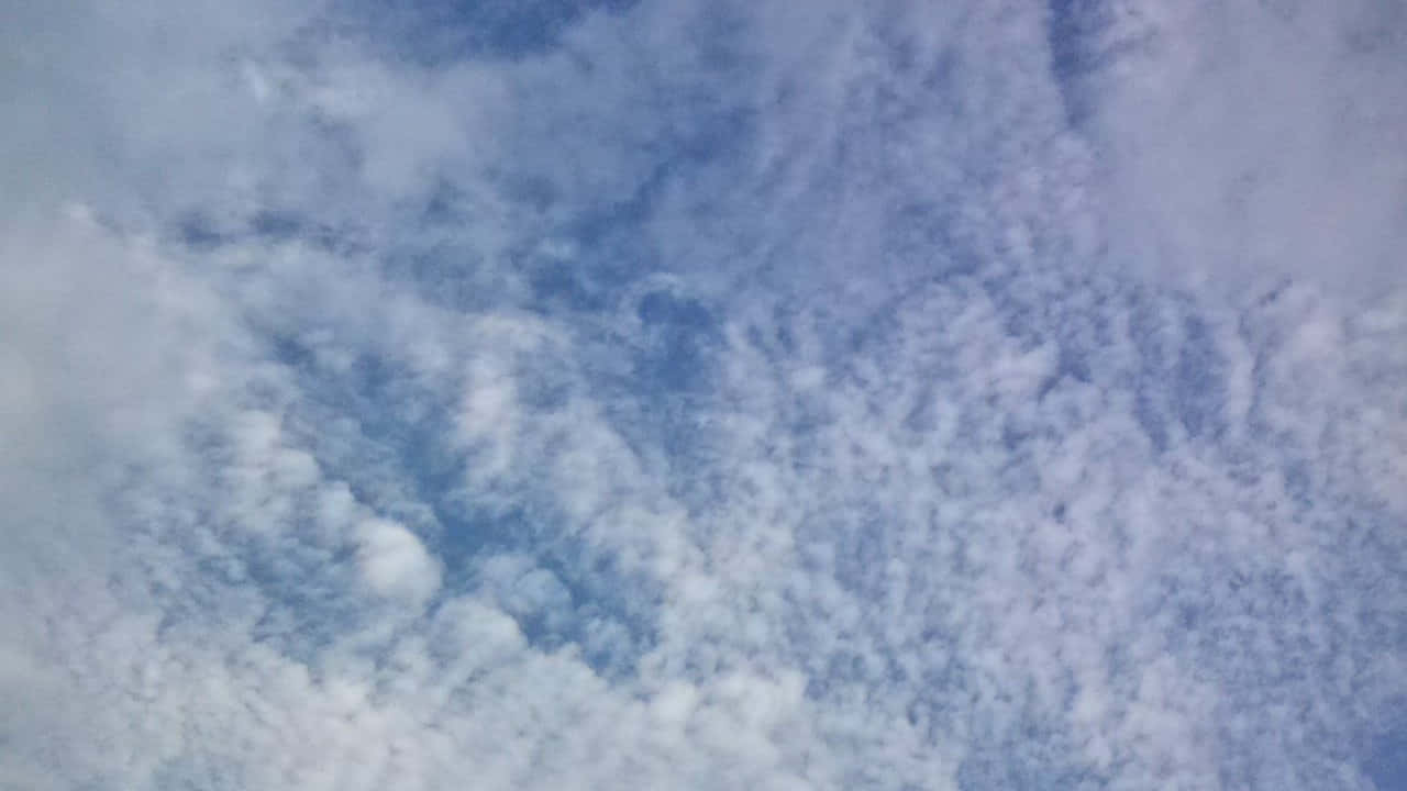 柔軟的白雲在平靜的藍天上飄浮，帶有柔和紋理。