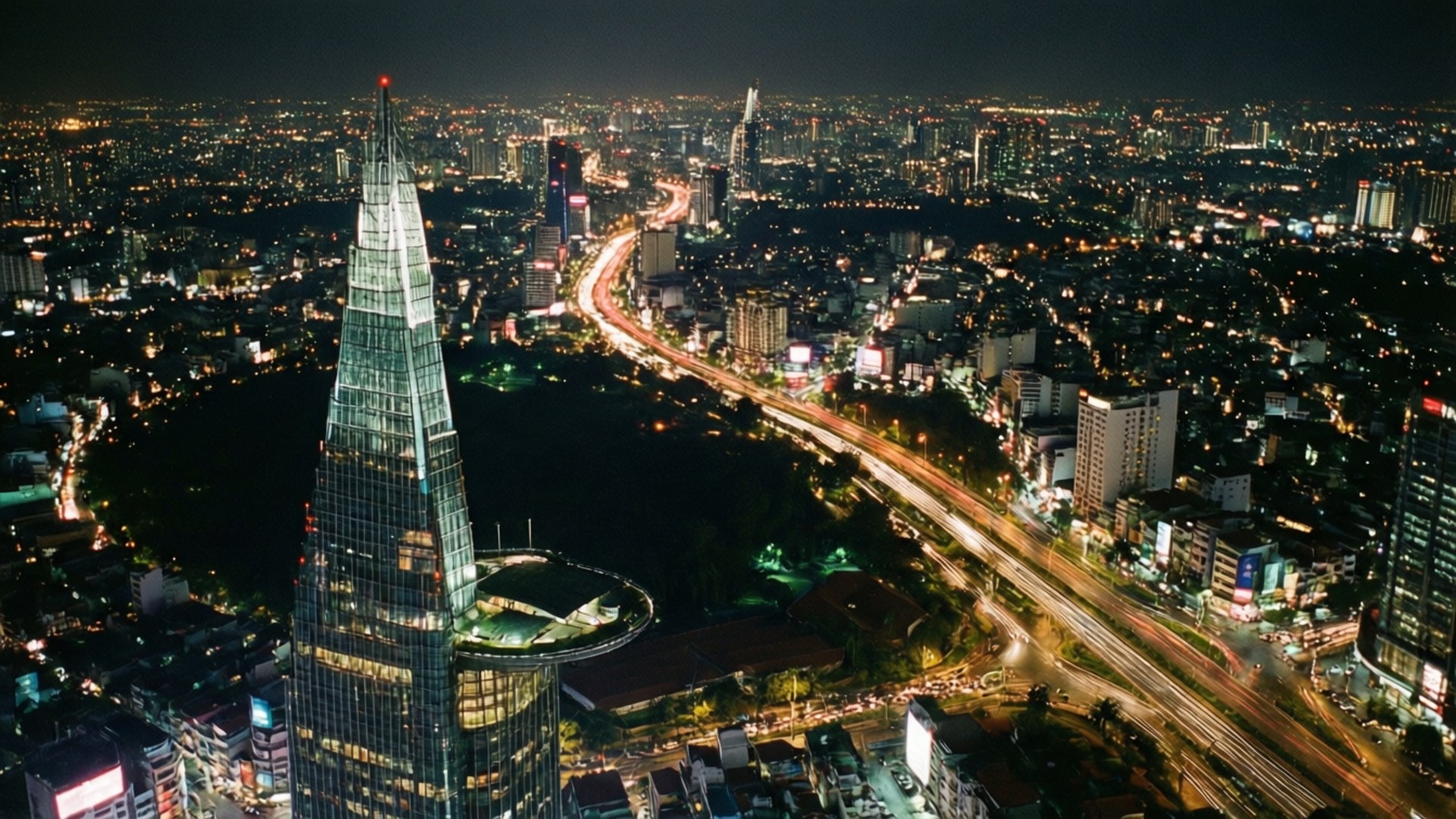 現代城市的空中夜景，帶有玻璃摩天大樓和發光燈光。