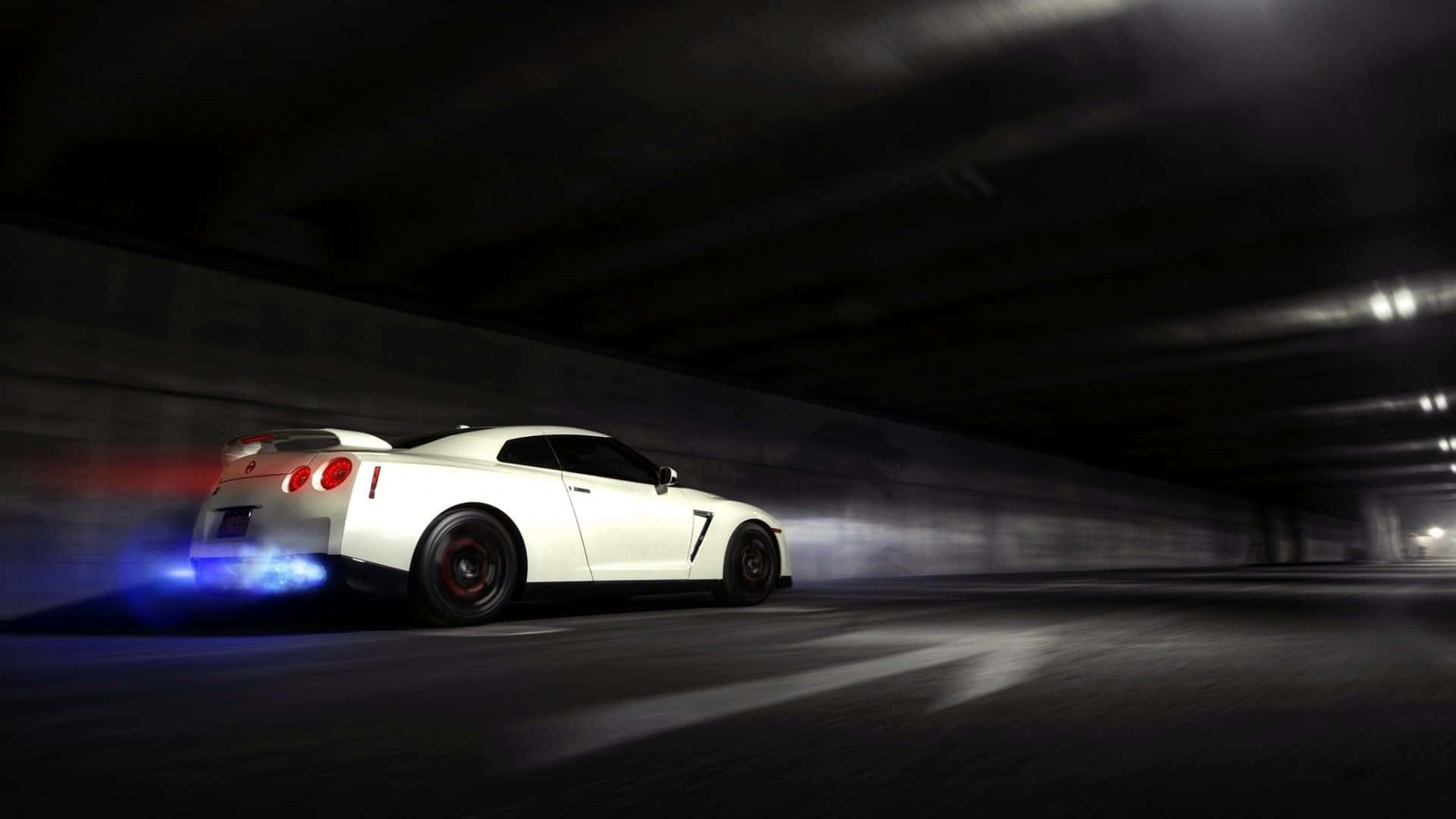酷炫日產Skyline灰車 壁紙 — 一輛白色跑車在黑暗隧道中疾馳，帶有藍色排氣火焰和動態模糊效果。