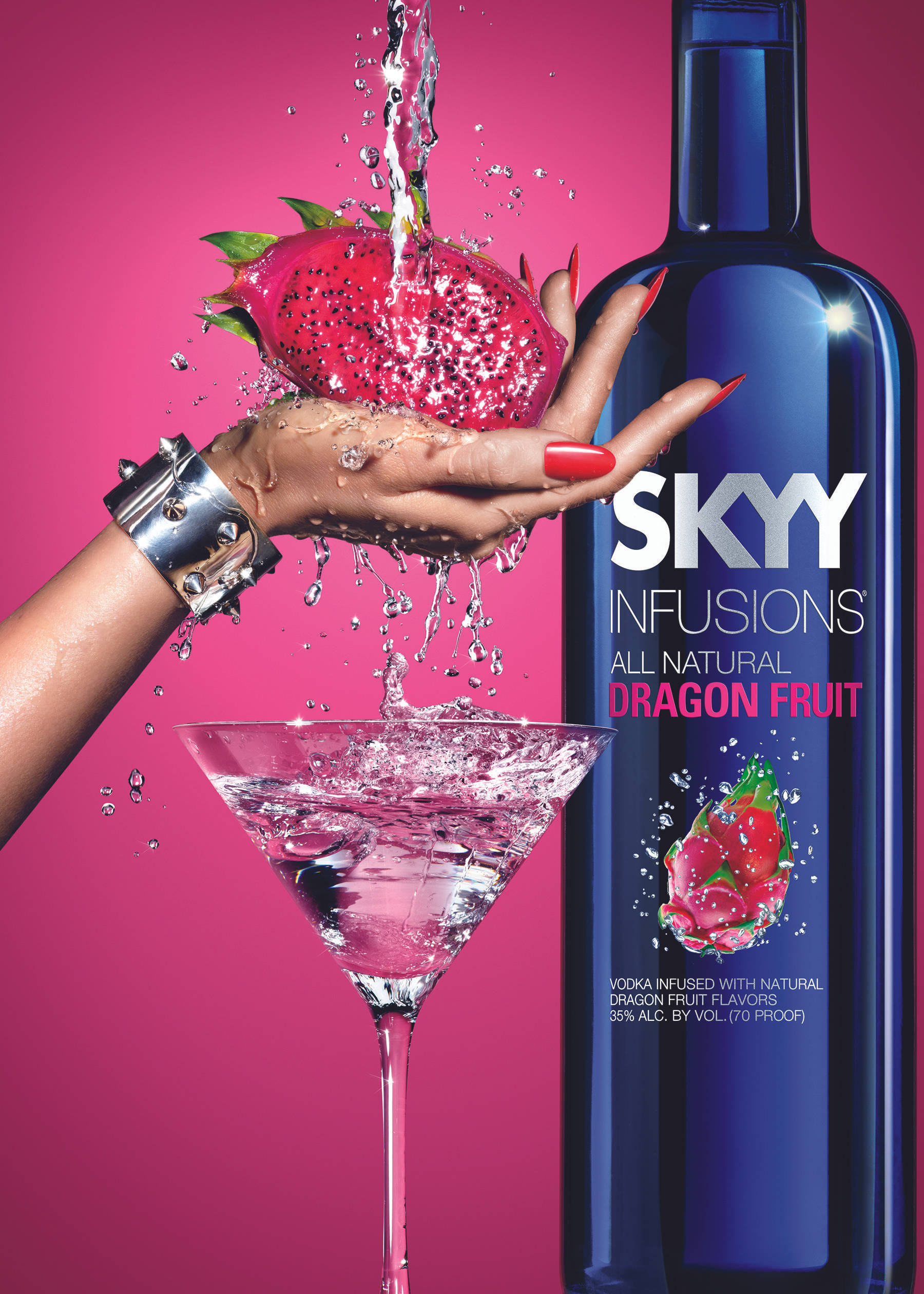 Skyy伏特加搭配火龍果片 壁紙 — 一隻紅色指甲的手拿著爆開的火龍果在馬天尼杯上方，粉紅色液體濺向充滿活力的洋紅色背景，旁邊有一個藍色伏特加酒瓶。