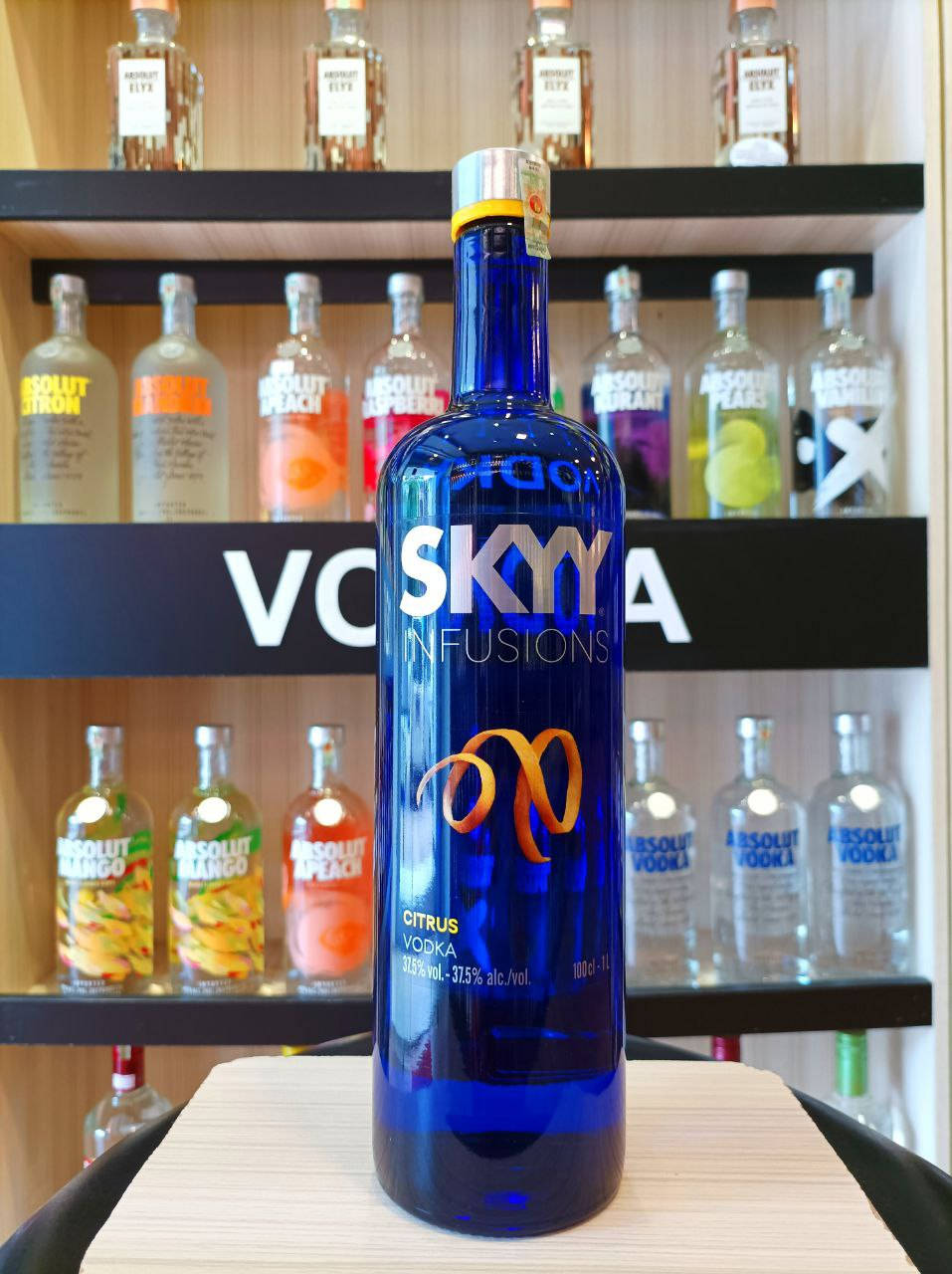 藍色 Sky Citrus 伏特加酒瓶在酒吧展示，後面架子上有 Absolut 伏特加酒瓶。