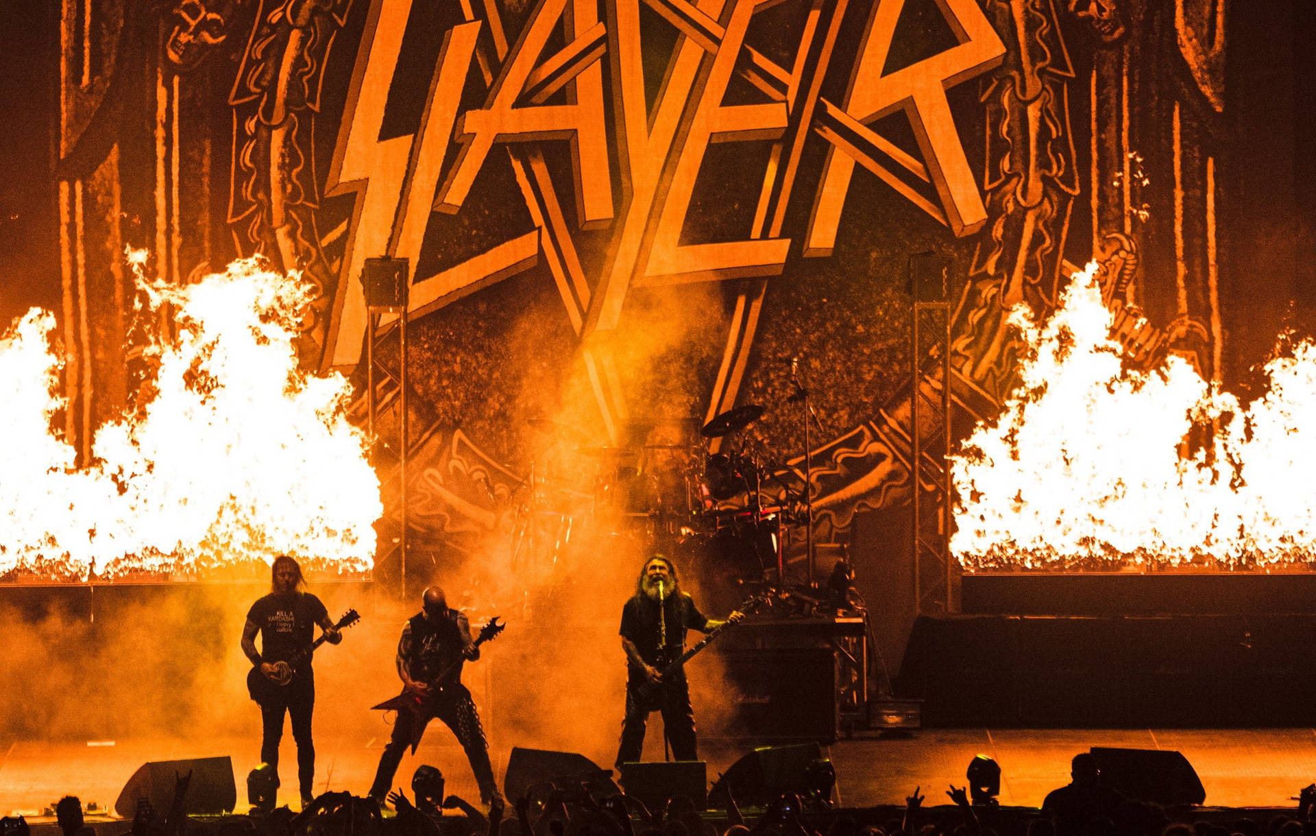 Slayer 樂隊在橙色燈光下於舞台上與火焰一同現場表演。