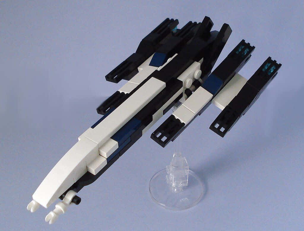 Normandy Sr-2 桌布 壁紙 — 一個時尚的黑白LEGO太空船模型，帶有藍色點綴，放置在透明支架上，背景是柔和的藍色。