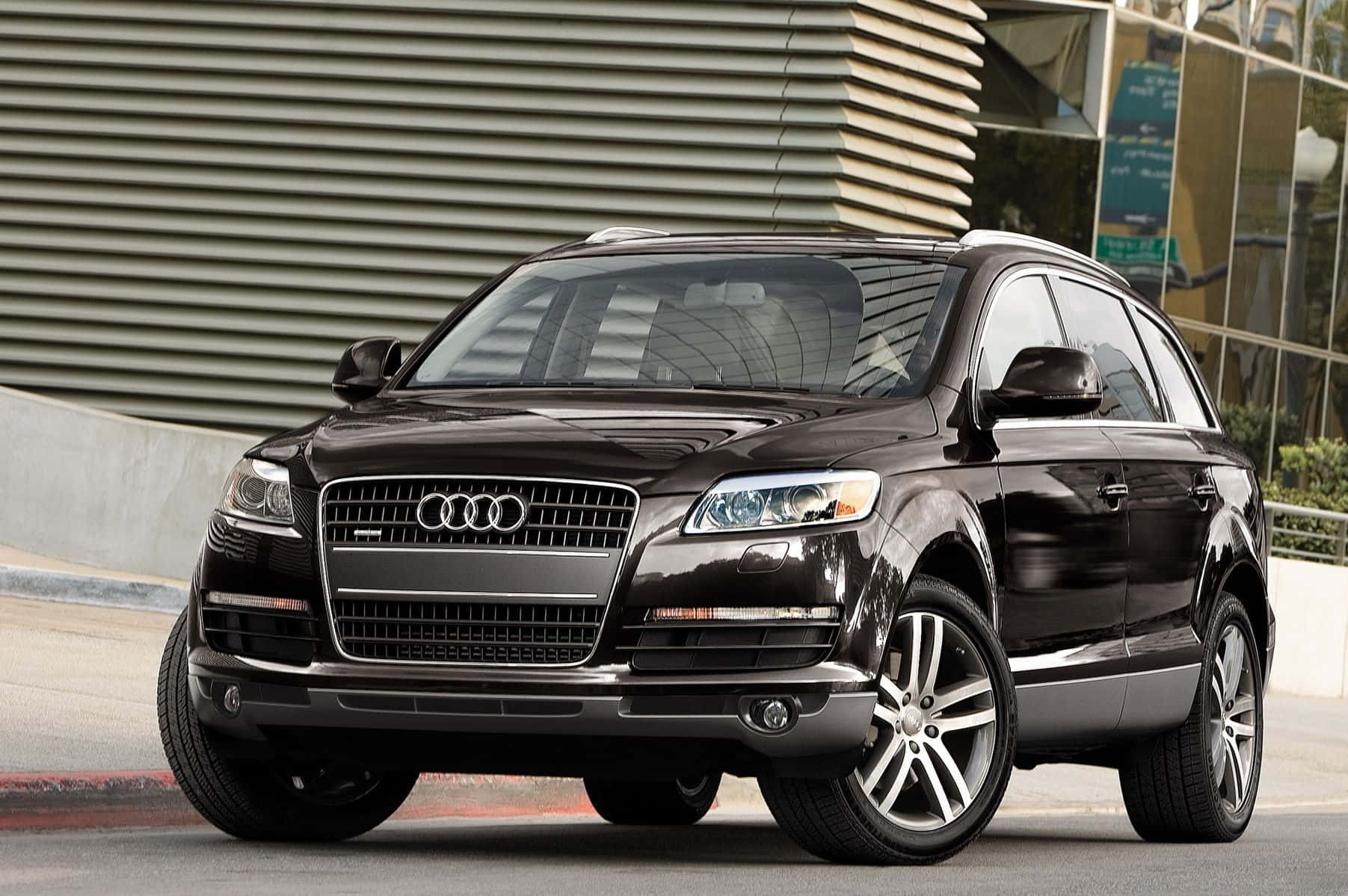 Audi Q7 桌布 壁紙 — 一輛時尚的黑色奧迪Q7 SUV停泊在城巿街道上，背景是現代建築。