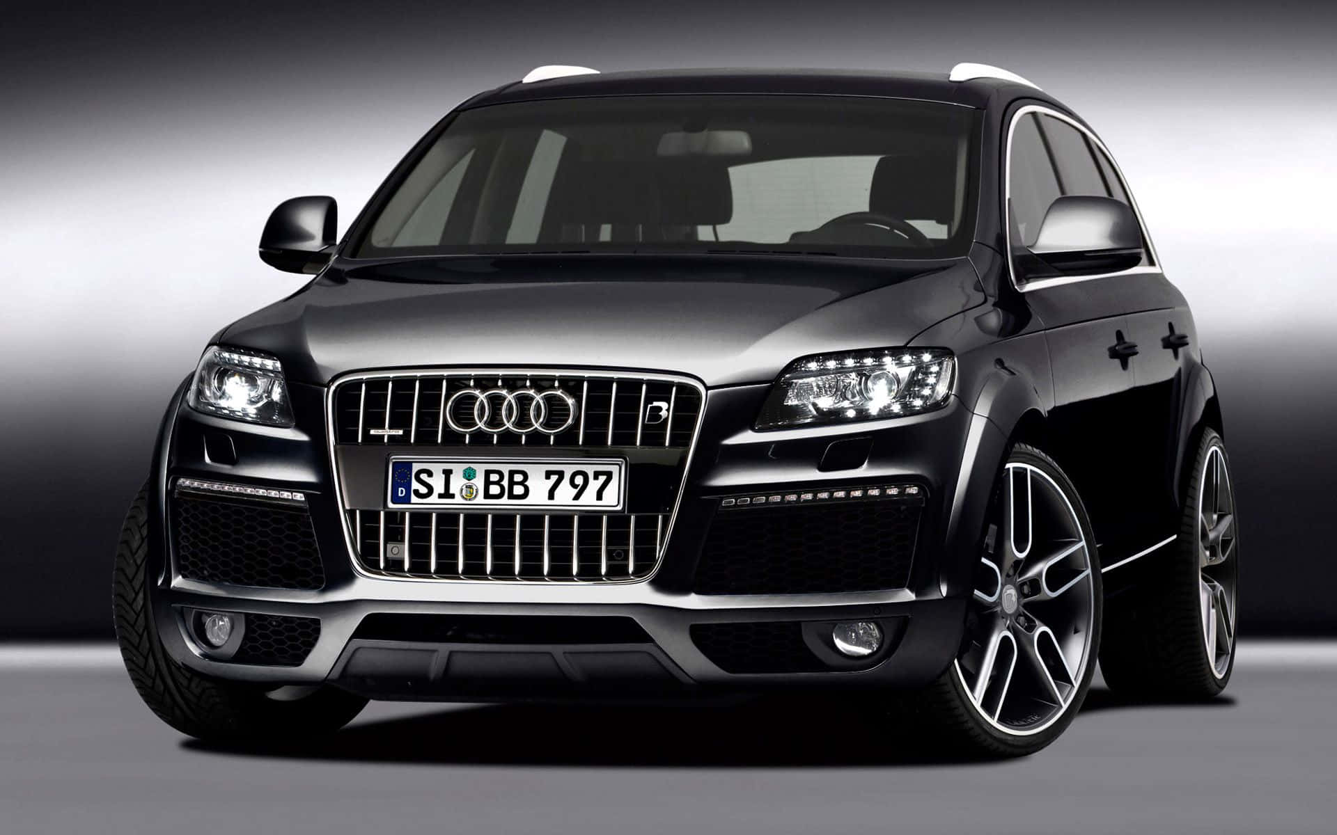 Audi Q7 桌布 壁紙 — 一輛時尚的黑色奧迪Q7 SUV，帶有鍍鉻裝飾和定制輪圈，在漸變灰色工作室背景前擺拍。