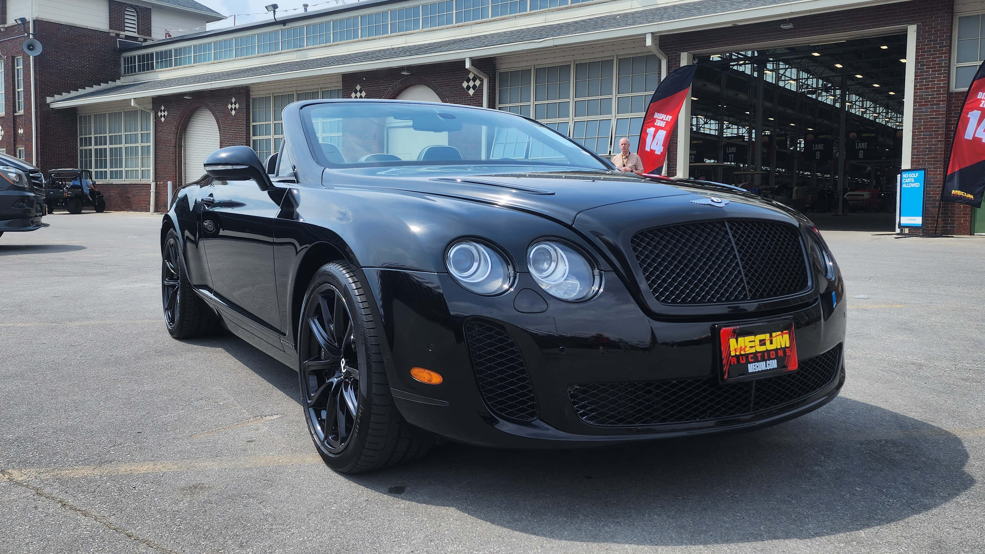 Bentley Continental Supersports 桌布 壁紙 — 一架時尚的黑色賓利開篷車停泊在磚砌車庫前，車庫有開放式車位和橫額。