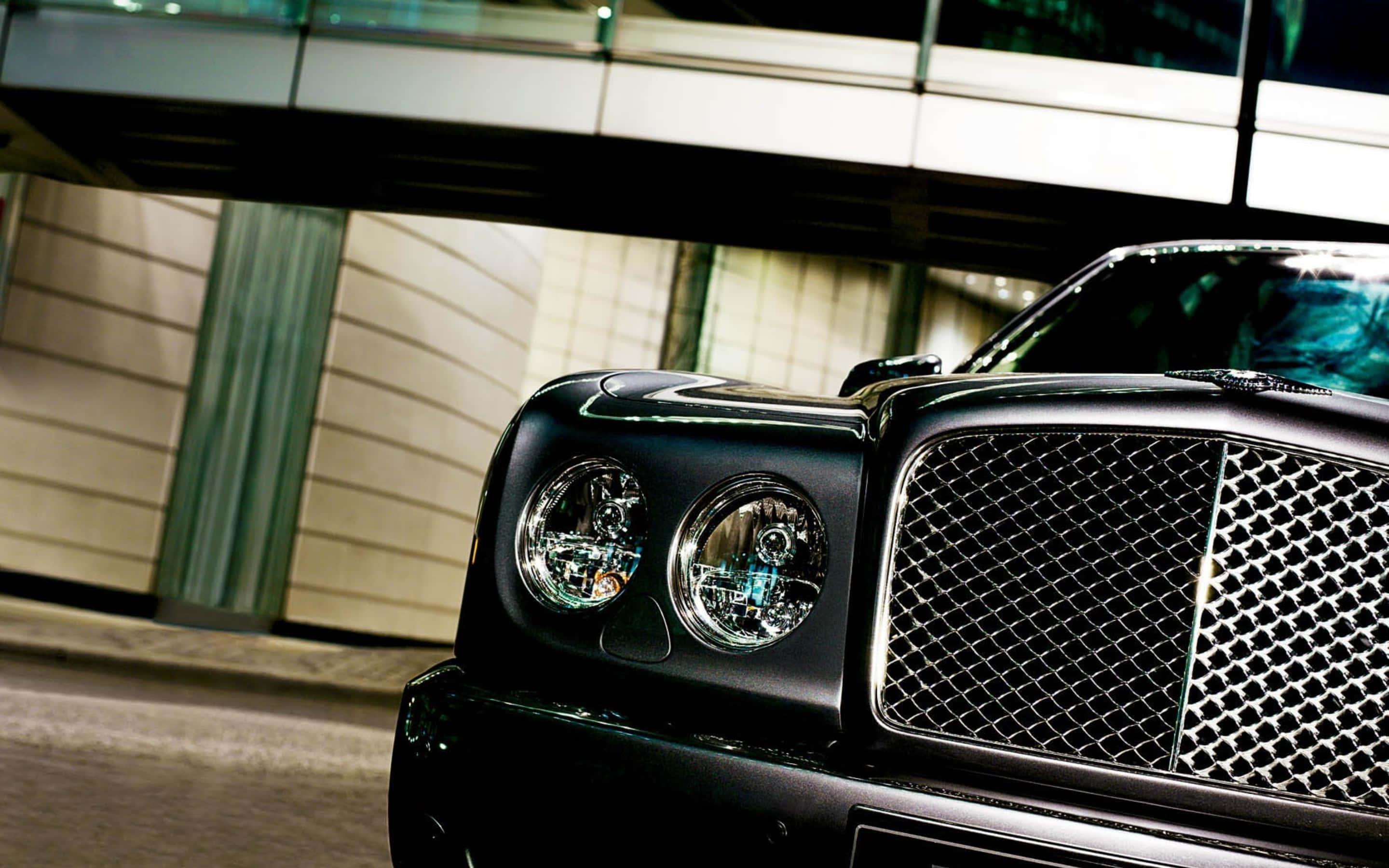 Bentley Arnage 桌布 壁紙 — 一輛時尚的黑色賓利豪華車在夜間城市燈光下閃閃發光，背景是一座現代建築。