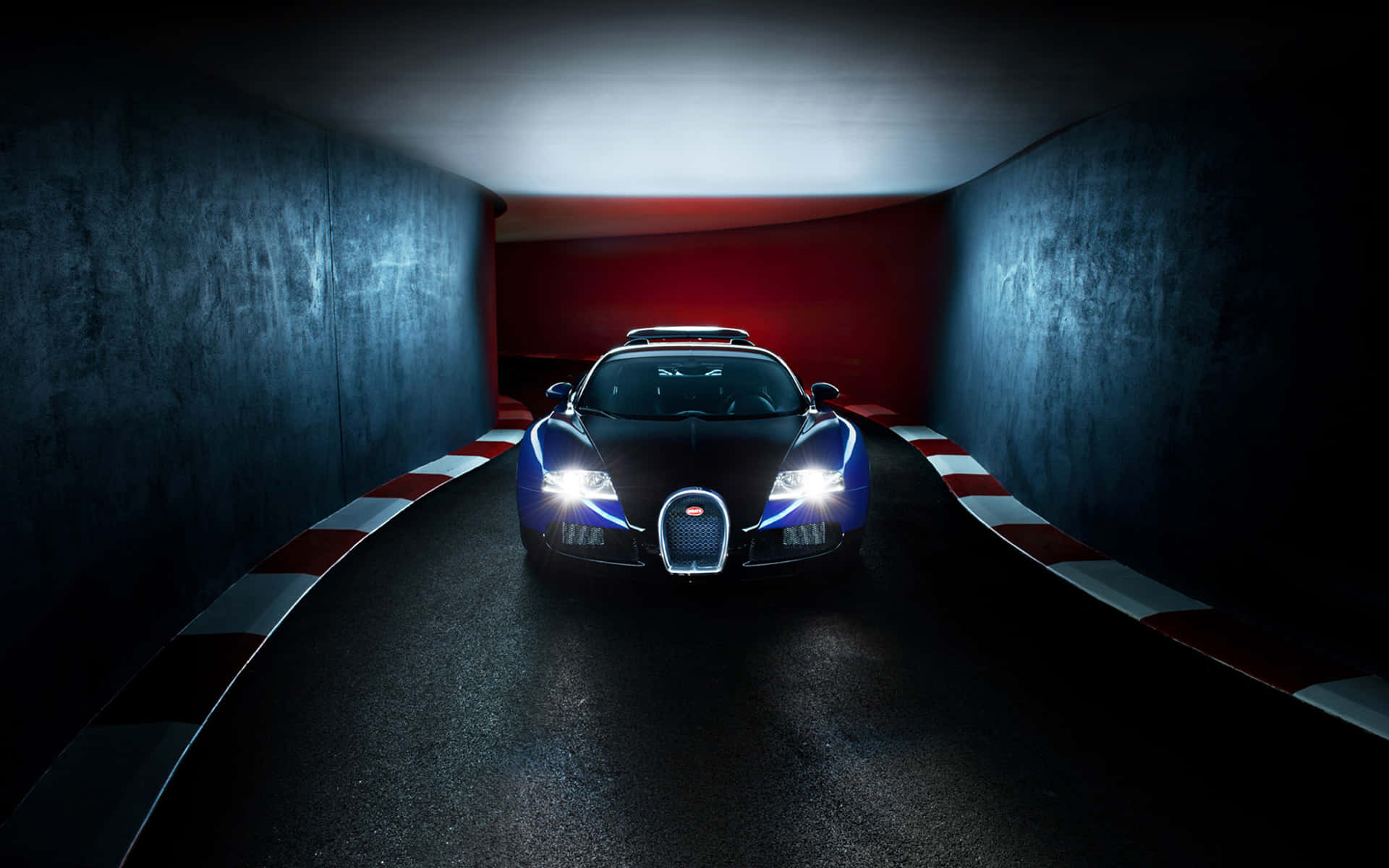 Bugatti Veyron 桌布 壁紙 — 一輛時尚的黑色 Bugatti 超級跑車，配備發光的藍色車頭燈，在佈滿紅白條紋護欄的黑暗隧道中疾馳。