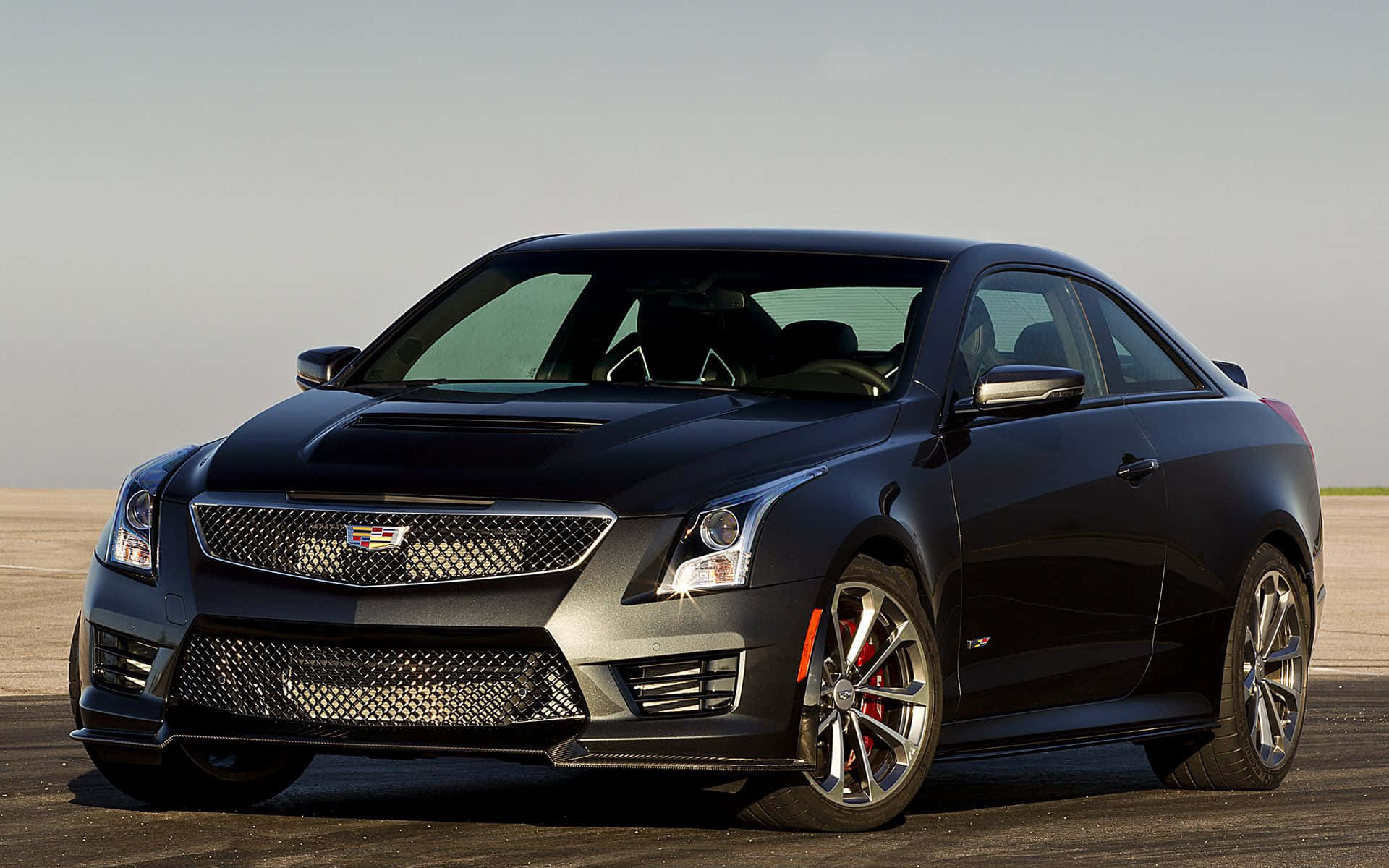 Cadillac Ats 桌布 壁紙 — 一輛時尚的黑色Cadillac CTS-V雙門跑車，配備紅色制動卡鉗，停放在晴朗天空下的開放式瀝青路面上。