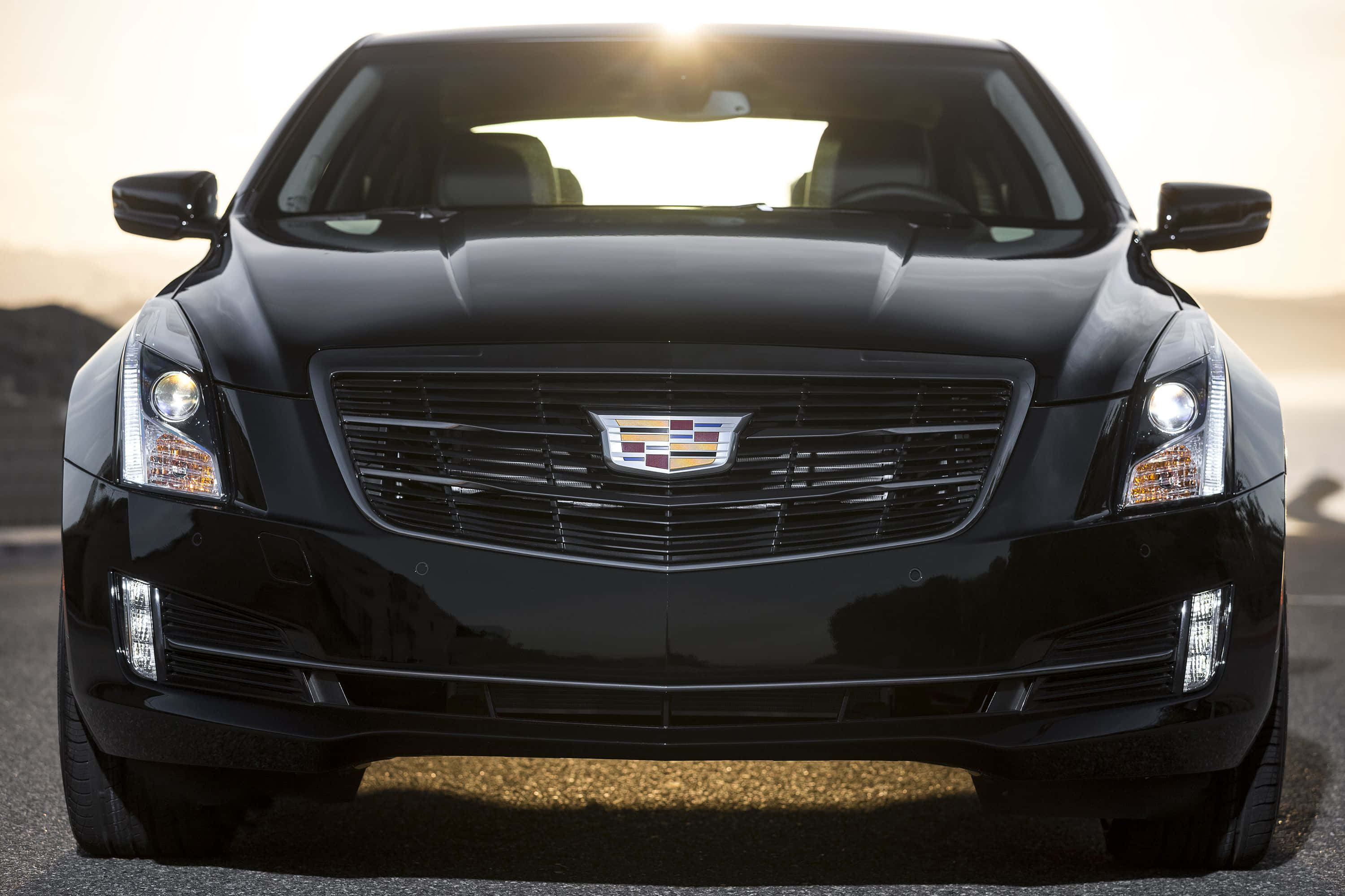 Cadillac Ats 桌布 壁紙 — 一輛時尚的黑色凱迪拉克轎車正面朝前，陽光在引擎蓋上閃爍，背景是朦朧的沙漠。