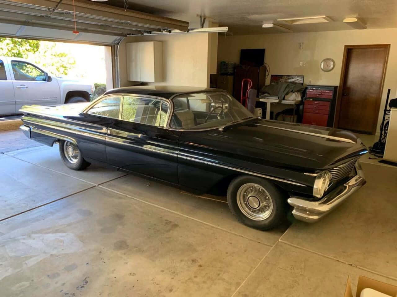 Pontiac Ventura 桌布 壁紙 — 一架時尚的黑色經典汽車帶有鍍鉻裝飾，停放在光線充足的車庫內，外面可見一輛白色卡車。
