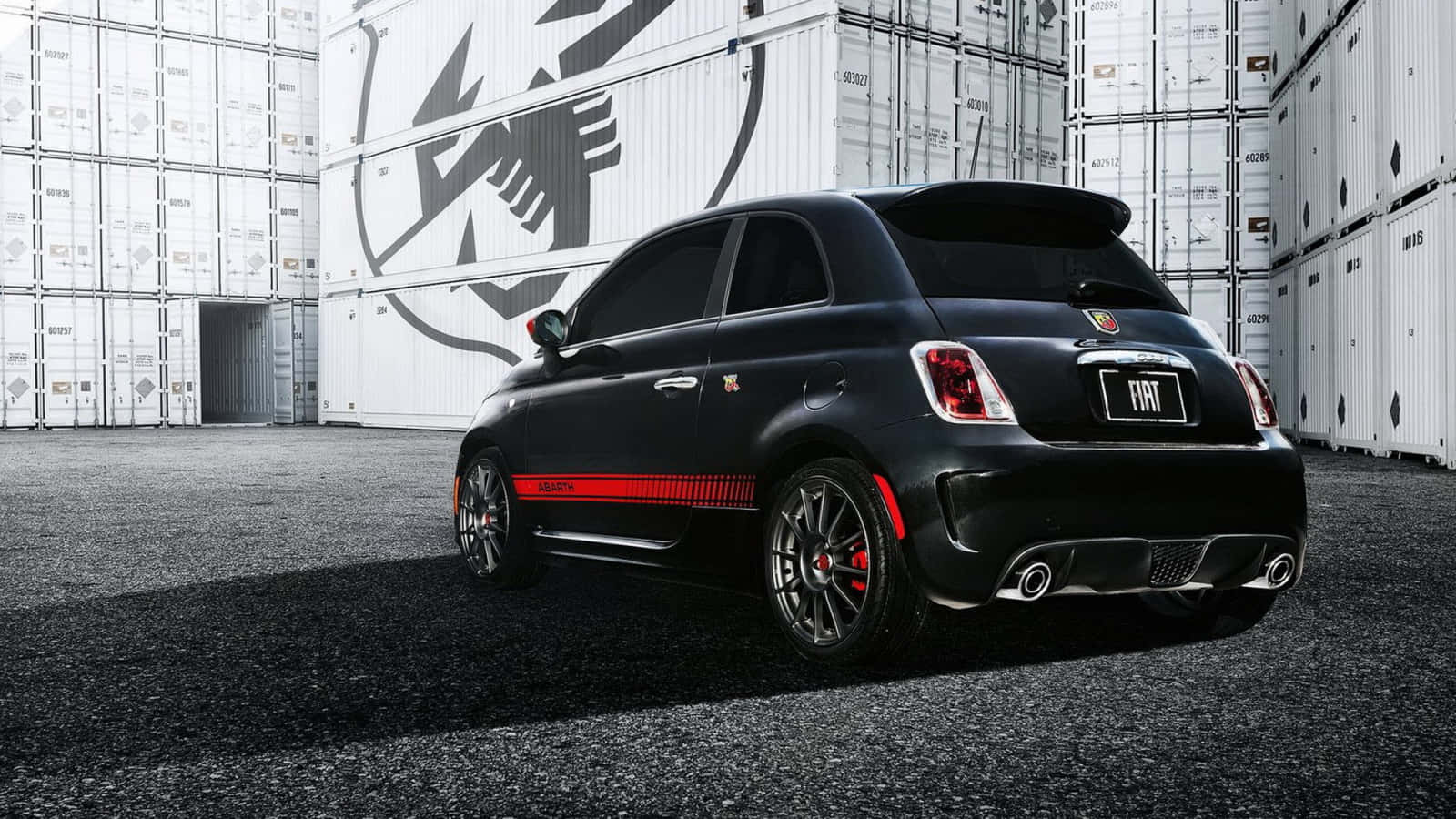 Fiat 500 桌布 壁紙 — 一架時尚黑色Fiat 500配紅色點綴，停放在堆疊的白色貨櫃前，光線明亮。