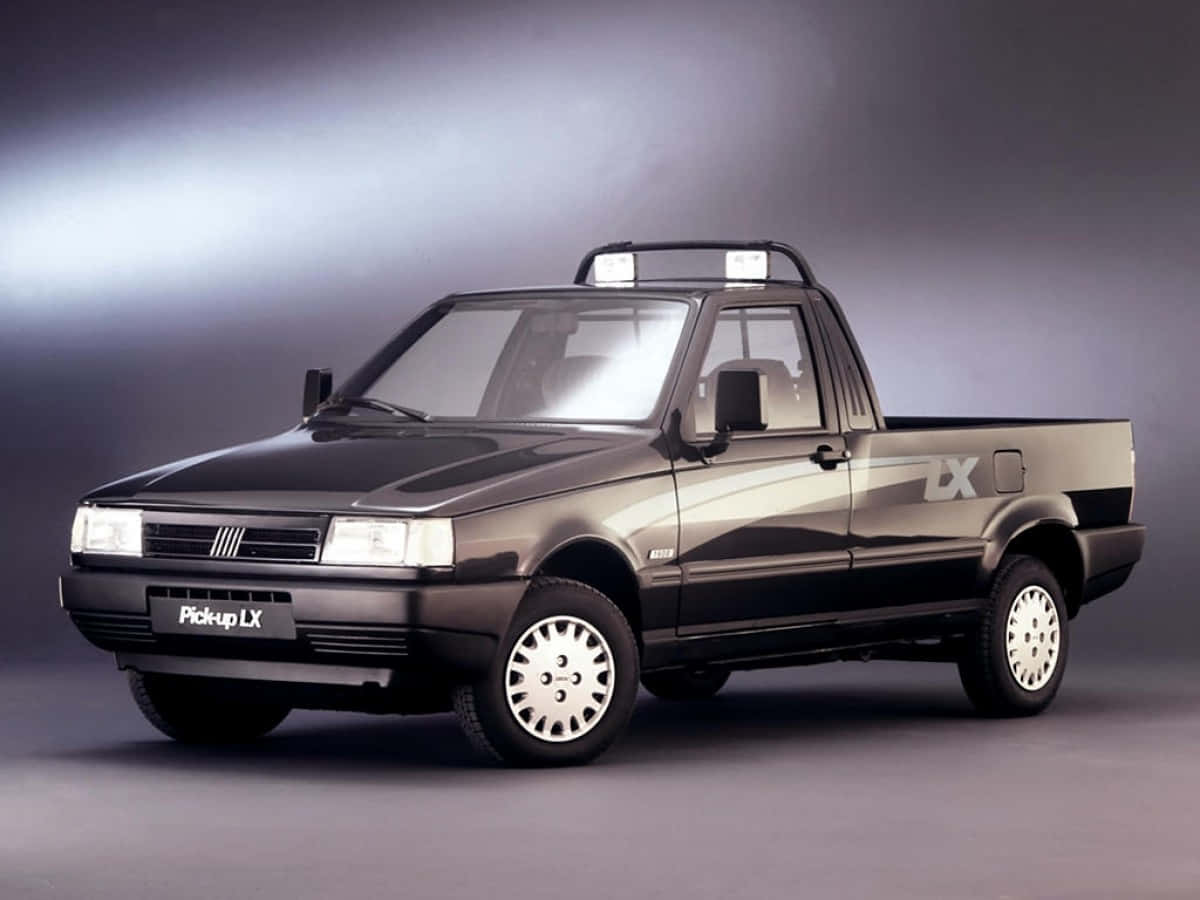 Fiat Fiorino 桌布 壁紙 — 一輛時尚的黑色Fiat皮卡車，配備銀色輪圈和車頂燈，在漸變灰色工作室背景前擺拍。
