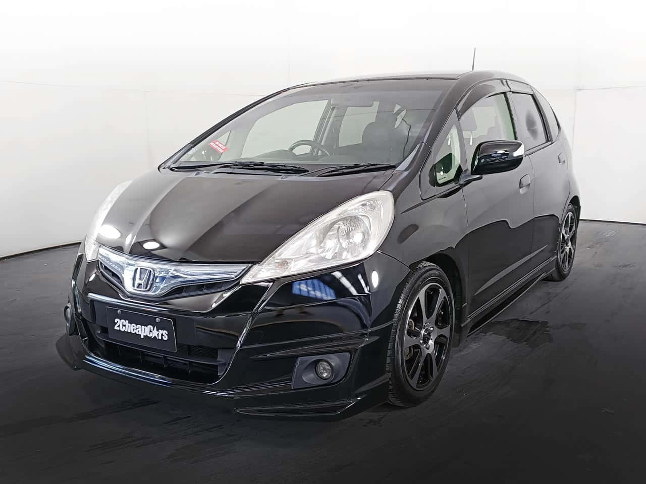 Honda Fit 桌布 壁紙 — 一輛時尚的黑色本田Jazz掀背車，配備定制合金輪圈，在極簡主義工作室環境中拍攝。