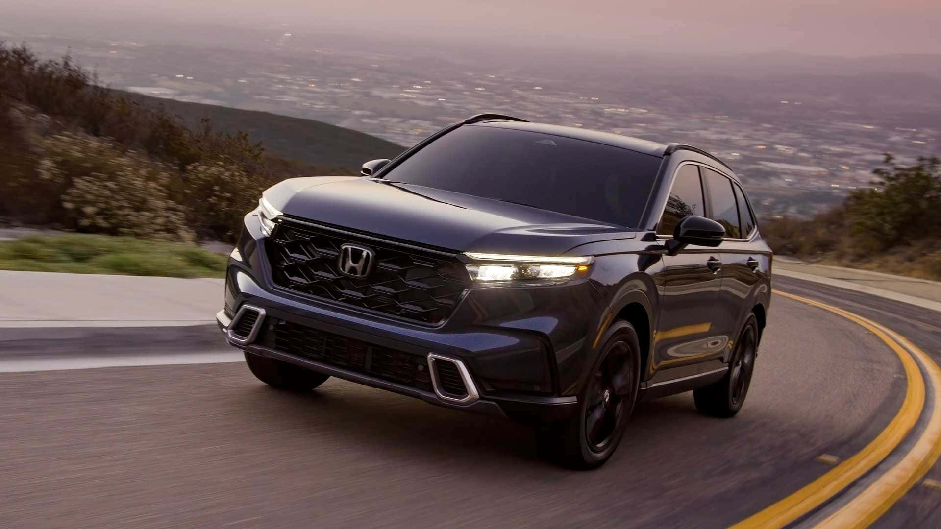 Honda Cr-v 桌布 壁紙 — 一輛時尚的黑色本田SUV在日落時分沿著蜿蜒的山路行駛，下方是廣闊的城市天際線。