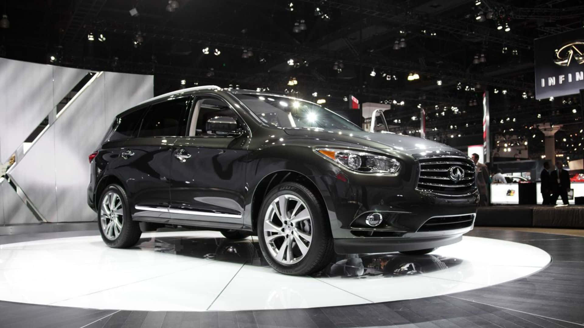 Infiniti Jx35 桌布 壁紙 — 一輛時尚的黑色Infiniti SUV在車展的圓形白色平台上，在明亮的展廳燈光下閃閃發光。