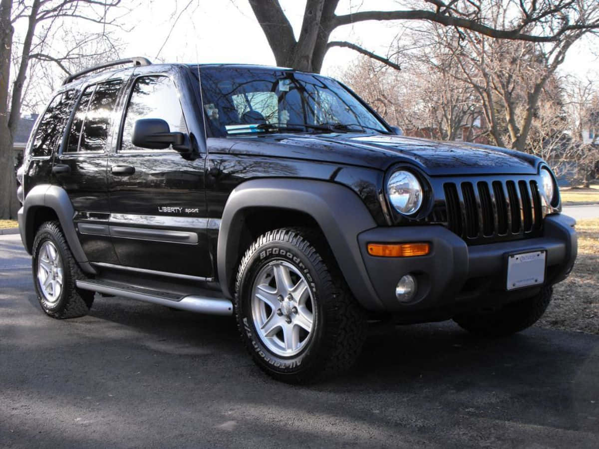 Jeep Liberty 桌布 壁紙 — 一輛時尚的黑色Jeep Liberty Sport SUV在晴朗的日子停泊在瀝青路上，周圍是光禿禿的樹木。