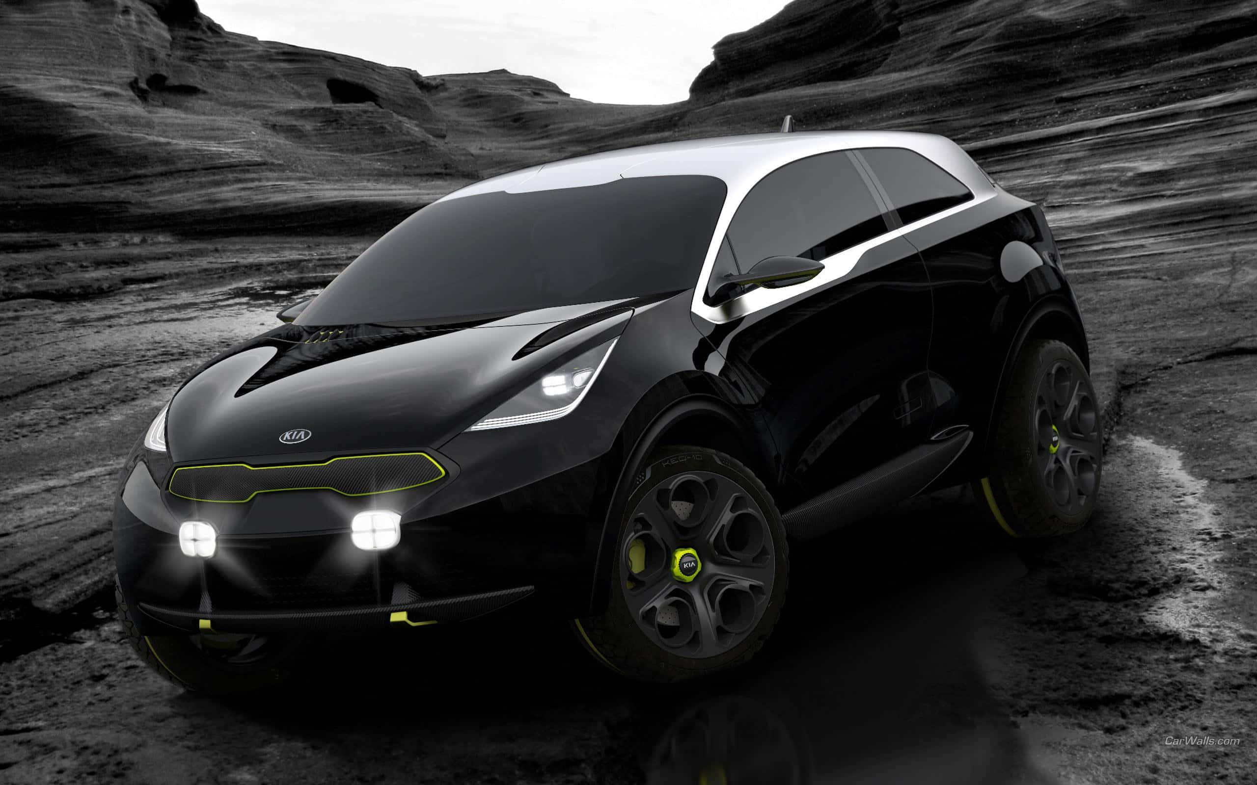 Kia Niro 桌布 壁紙 — 一輛時尚的黑色起亞概念車，帶有霓虹黃色點綴，停在崎嶇岩石地形上，天空柔和。