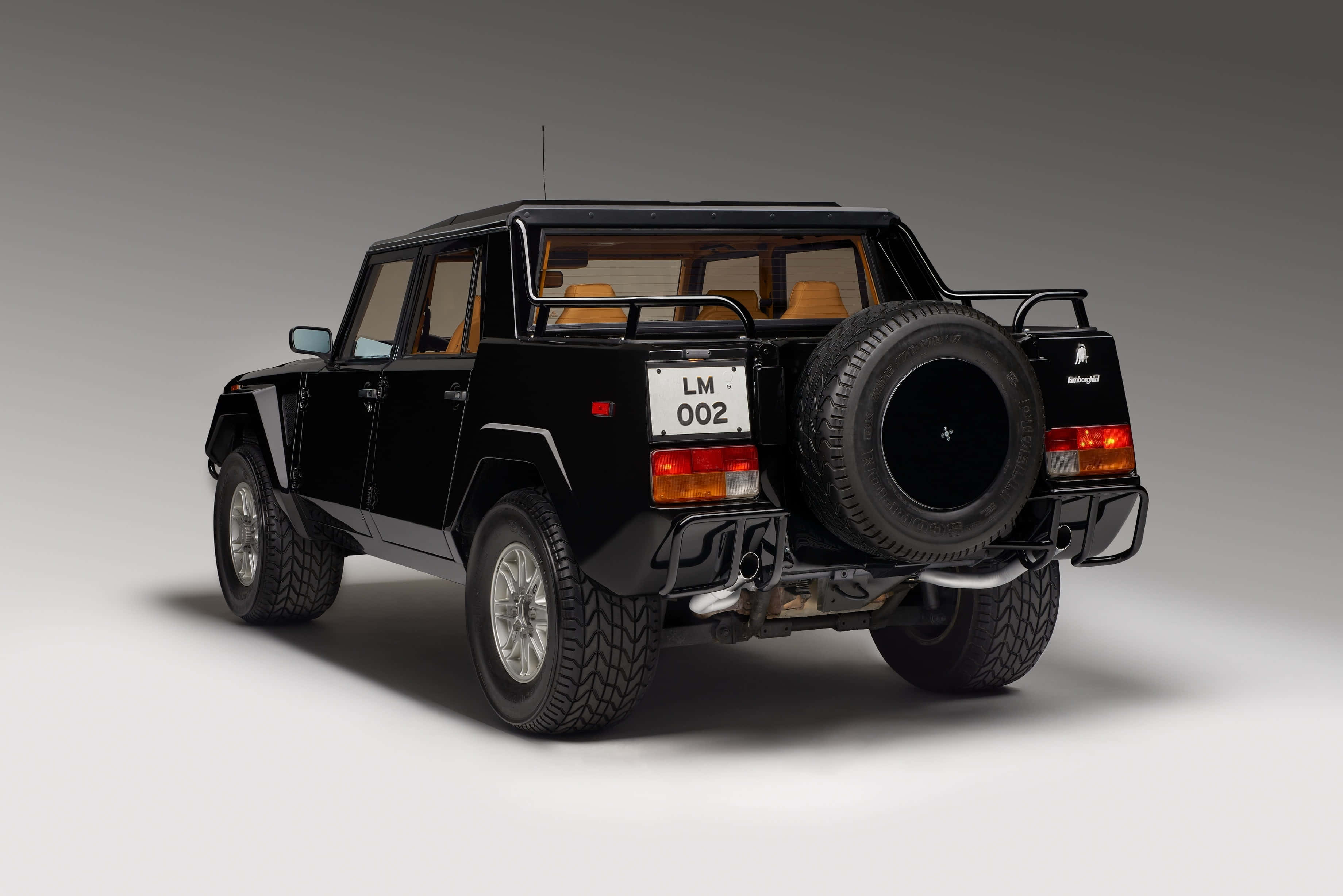 Lamborghini Lm002 桌布 壁紙 — 一輛時尚的黑色林寶堅尼LM002豪華越野車，從後方四分之三角度拍攝，背景為中性攝影棚。