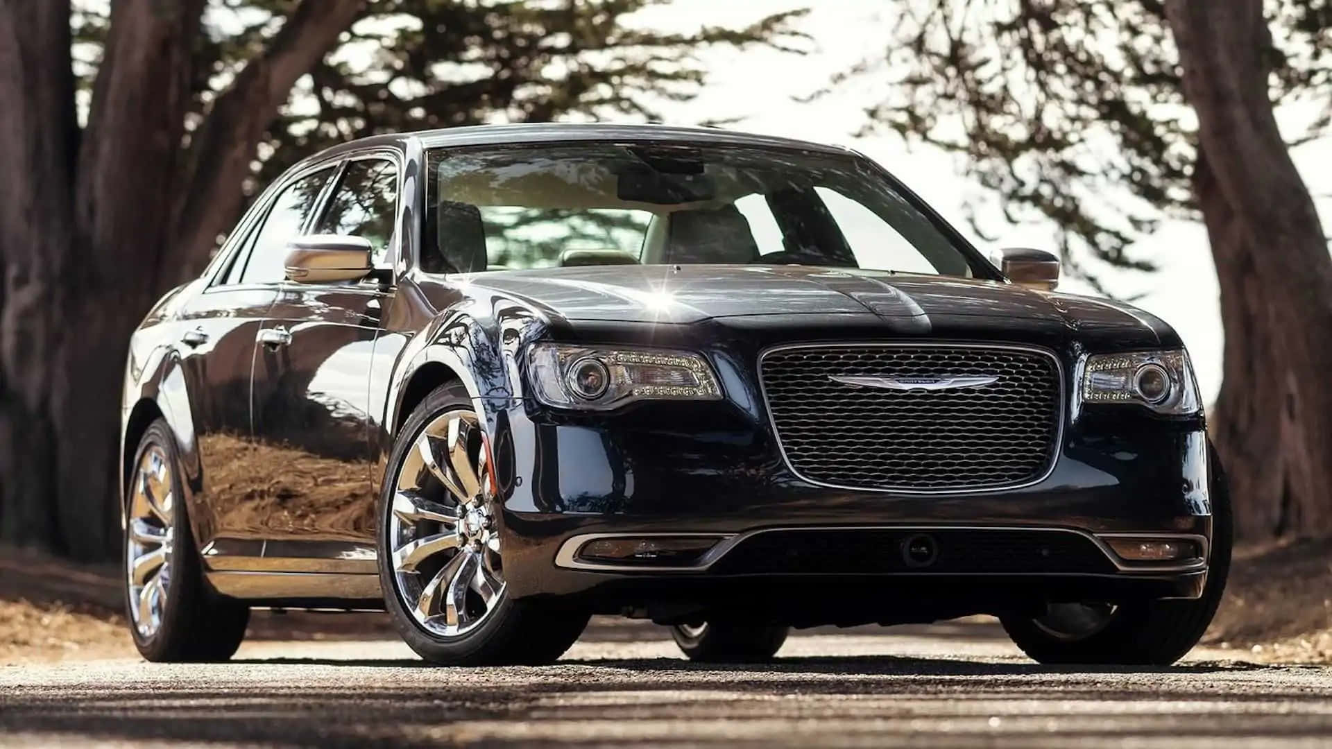 Chrysler 300 桌布 壁紙 — 一輛時尚的黑色豪華轎車在明亮的陽光下閃閃發光，停在一條綠樹成蔭的道路上。