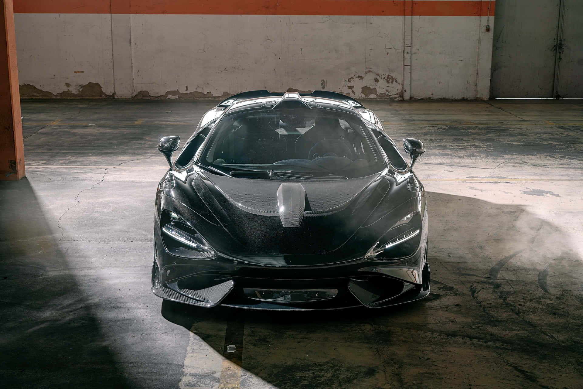 Mclaren 765lt 桌布 壁紙 — 一架型格黑色McLaren跑車在骯髒的工業車庫中，在戲劇性燈光下閃閃發光。