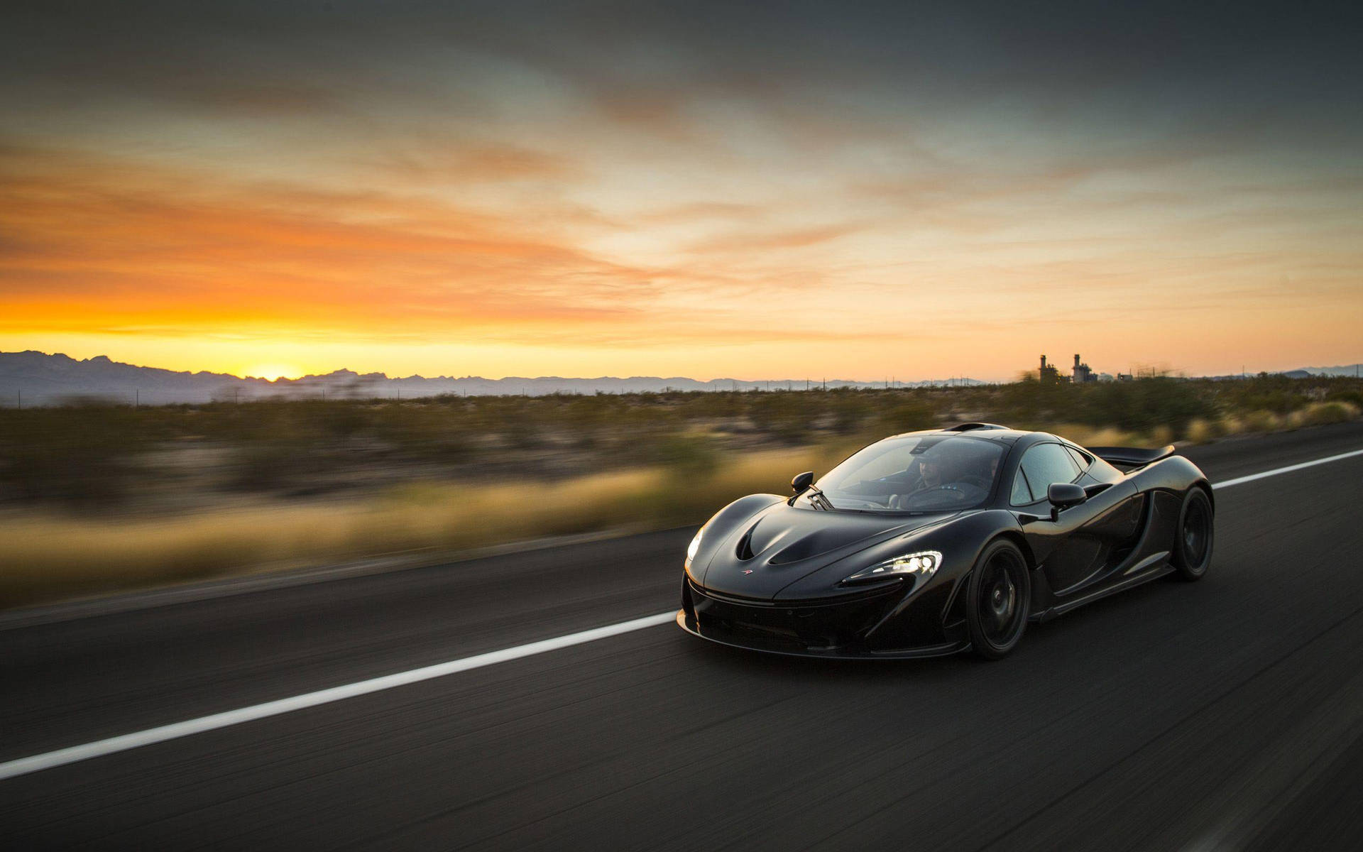 黑色McLaren超級跑車在日落時分在沙漠高速公路上疾馳。