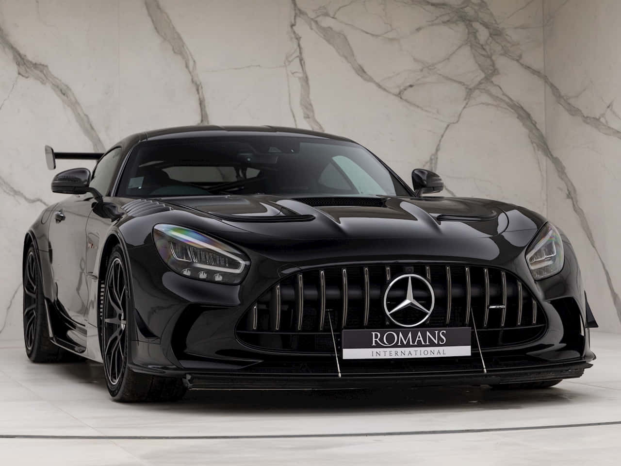 Mercedes Benz Amg Gt 桌布 壁紙 — 一輛時尚的黑色Mercedes-AMG GT Black Series跑車在攝影棚燈光下，以白色大理石牆為背景閃閃發光。