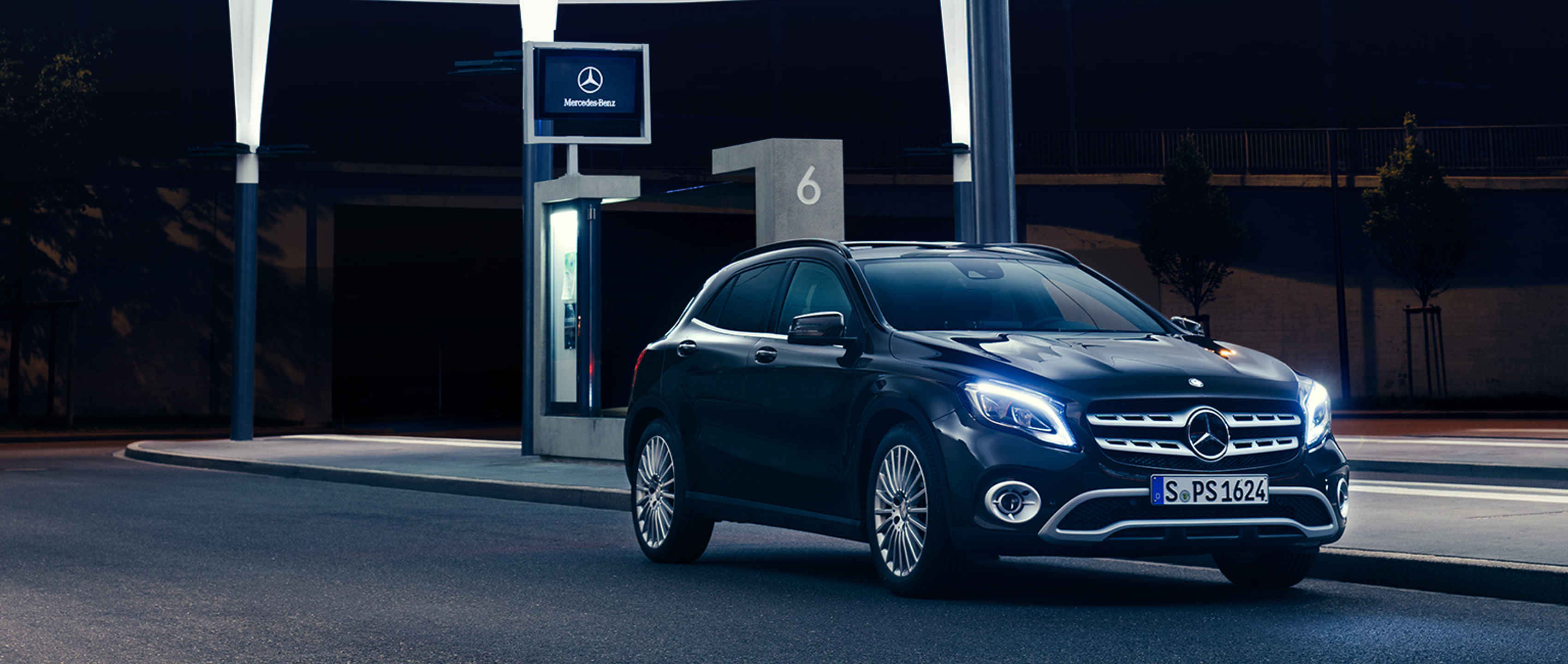 Mercedes Benz Gla-class 桌布 壁紙 — 一輛時尚的黑色Mercedes-Benz GLA-Class SUV，在夜空中被現代充電站的車頭燈照亮。