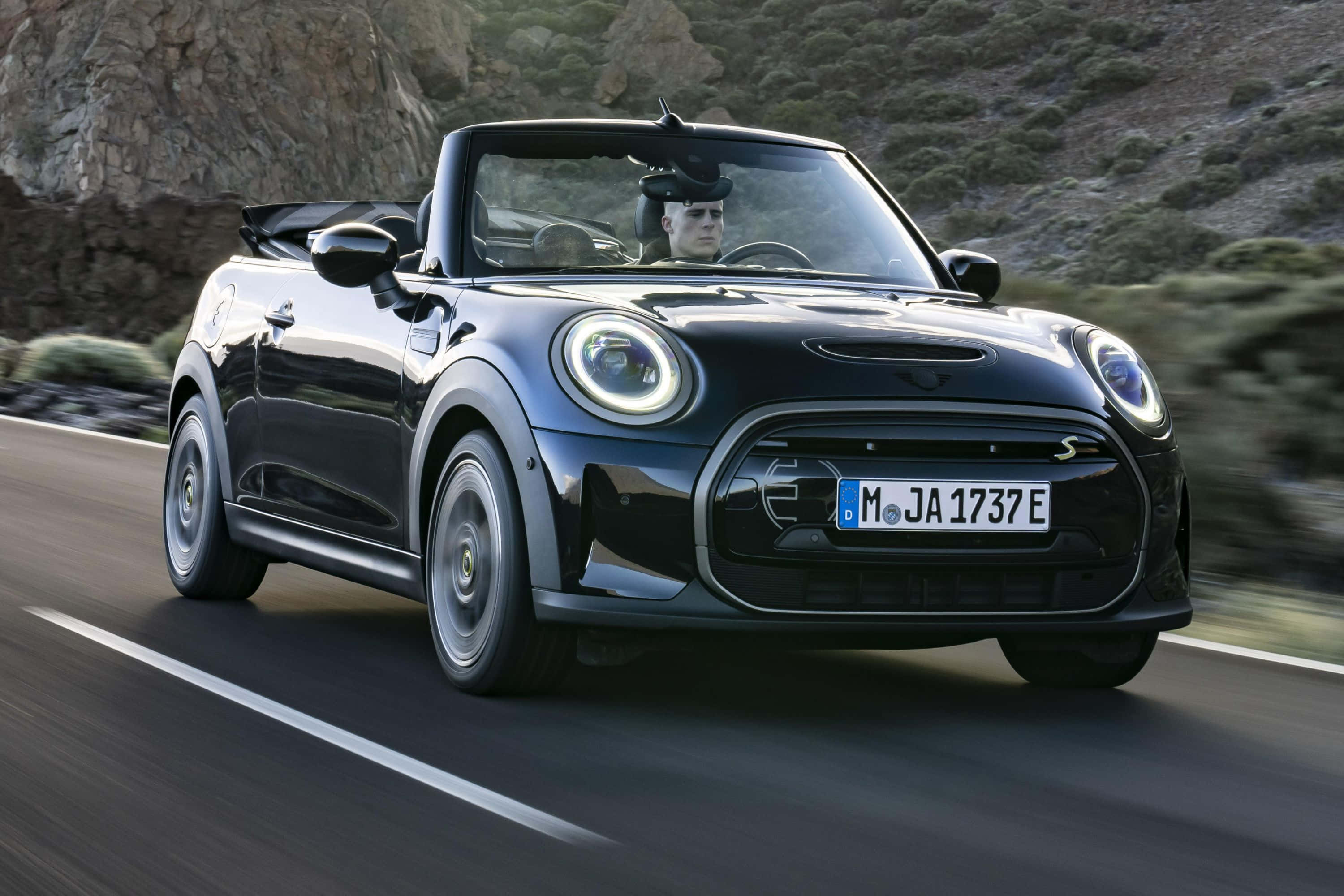 Mini Cooper S Convertible 桌布 壁紙 — 一輛時尚的黑色MINI Cooper S Convertible在蜿蜒的山路上疾馳，司機手握方向盤。