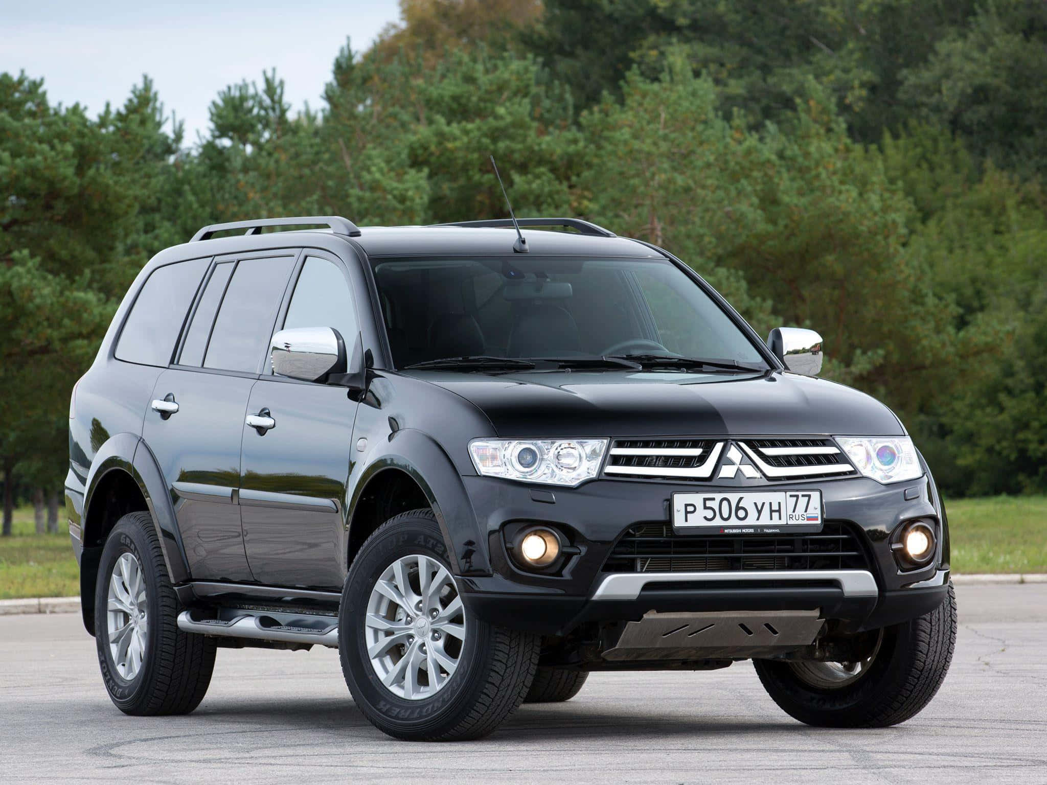 Mitsubishi Pajero 桌布 壁紙 — 一輛時尚的黑色三菱帕杰羅運動版SUV在日光下停在瀝青路上，背景是森林。