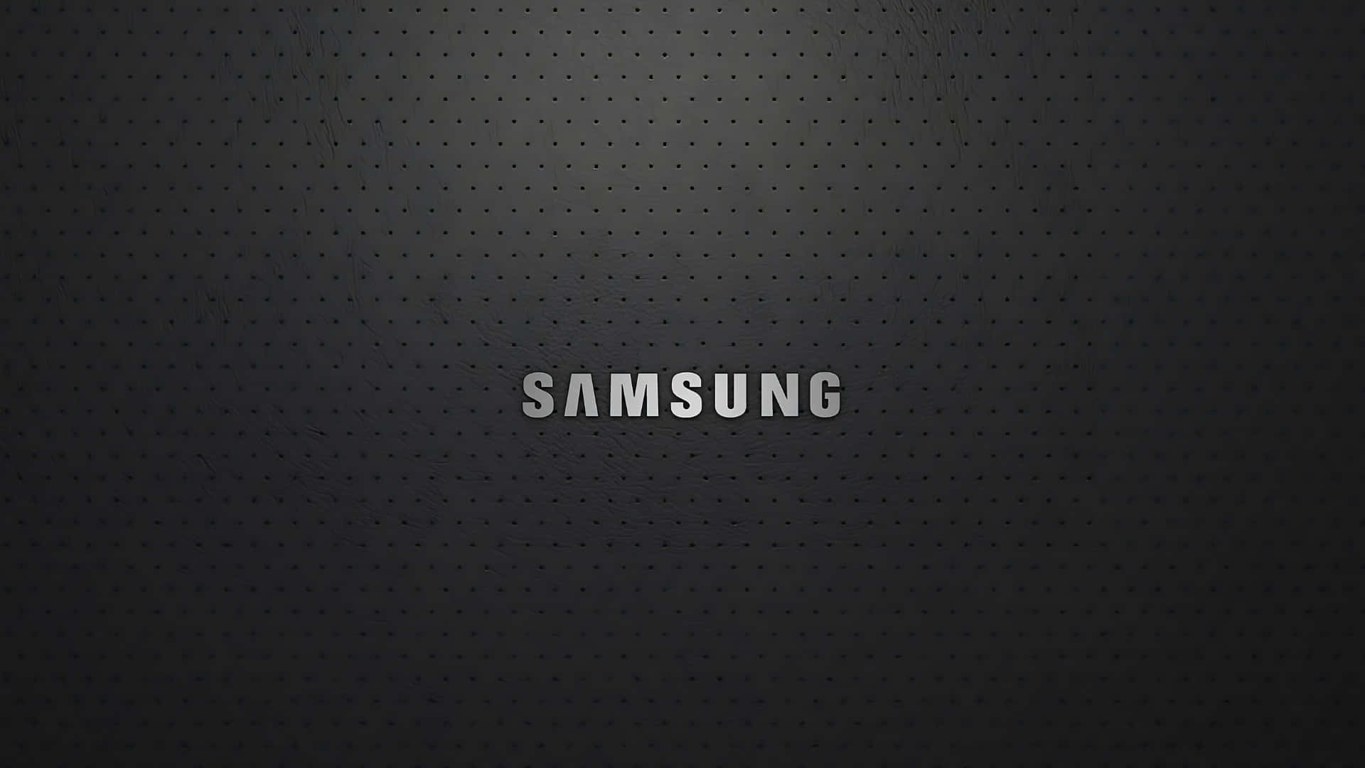  壁紙 — 時尚黑色穿孔表面帶有細微漸變，中央以金屬銀色顯示samsung字樣。