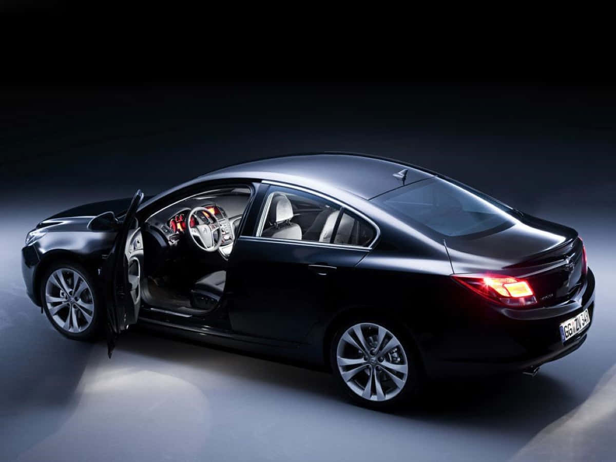 Opel Insignia 桌布 壁紙 — 一輛時尚的黑色轎車，車門打開，尾燈發光，在黑暗的攝影棚中展示，帶有戲劇性的聚光燈。
