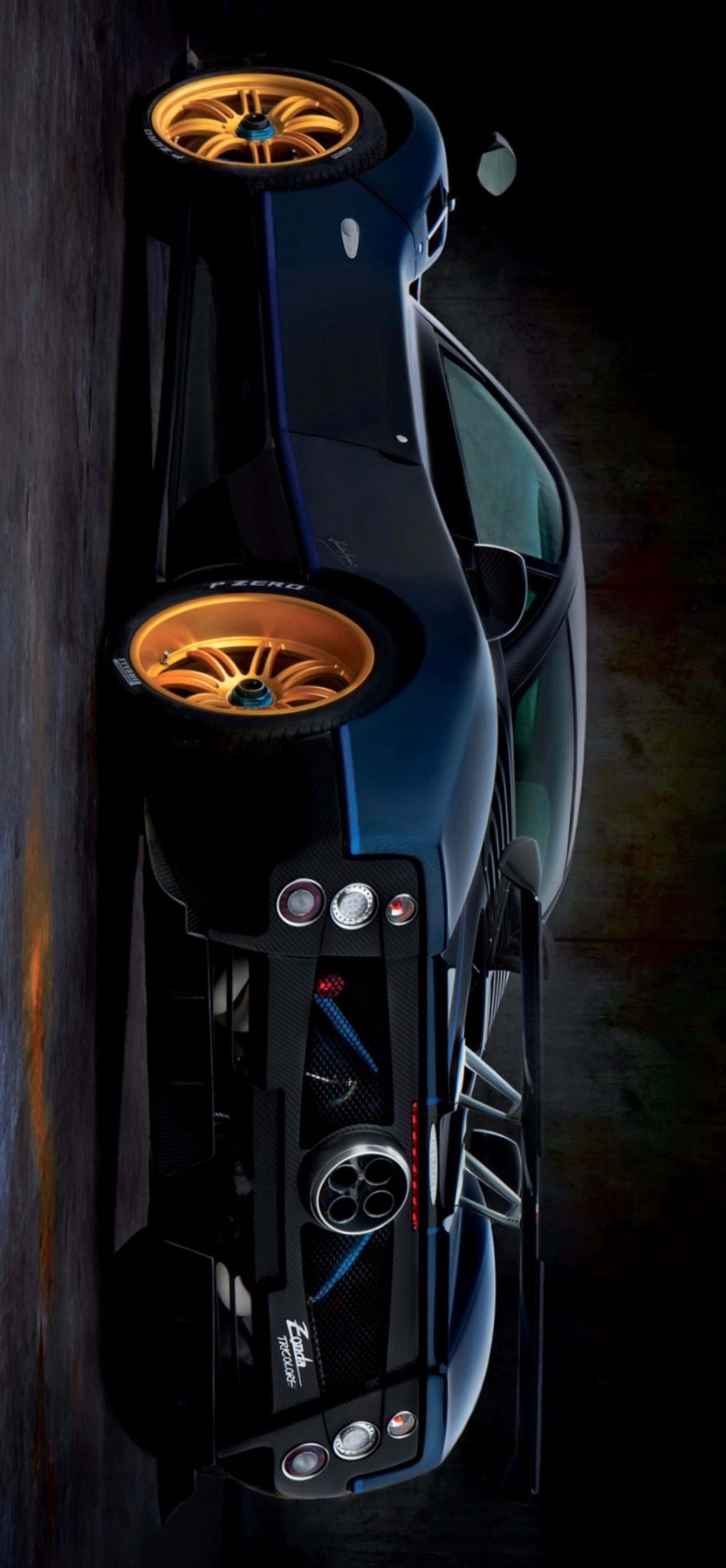 Pagani Zonda Tricolore 桌布 壁紙 — 一輛時尚黑色跑車配金色輪圈，從上方俯瞰，背景為深色紋理。