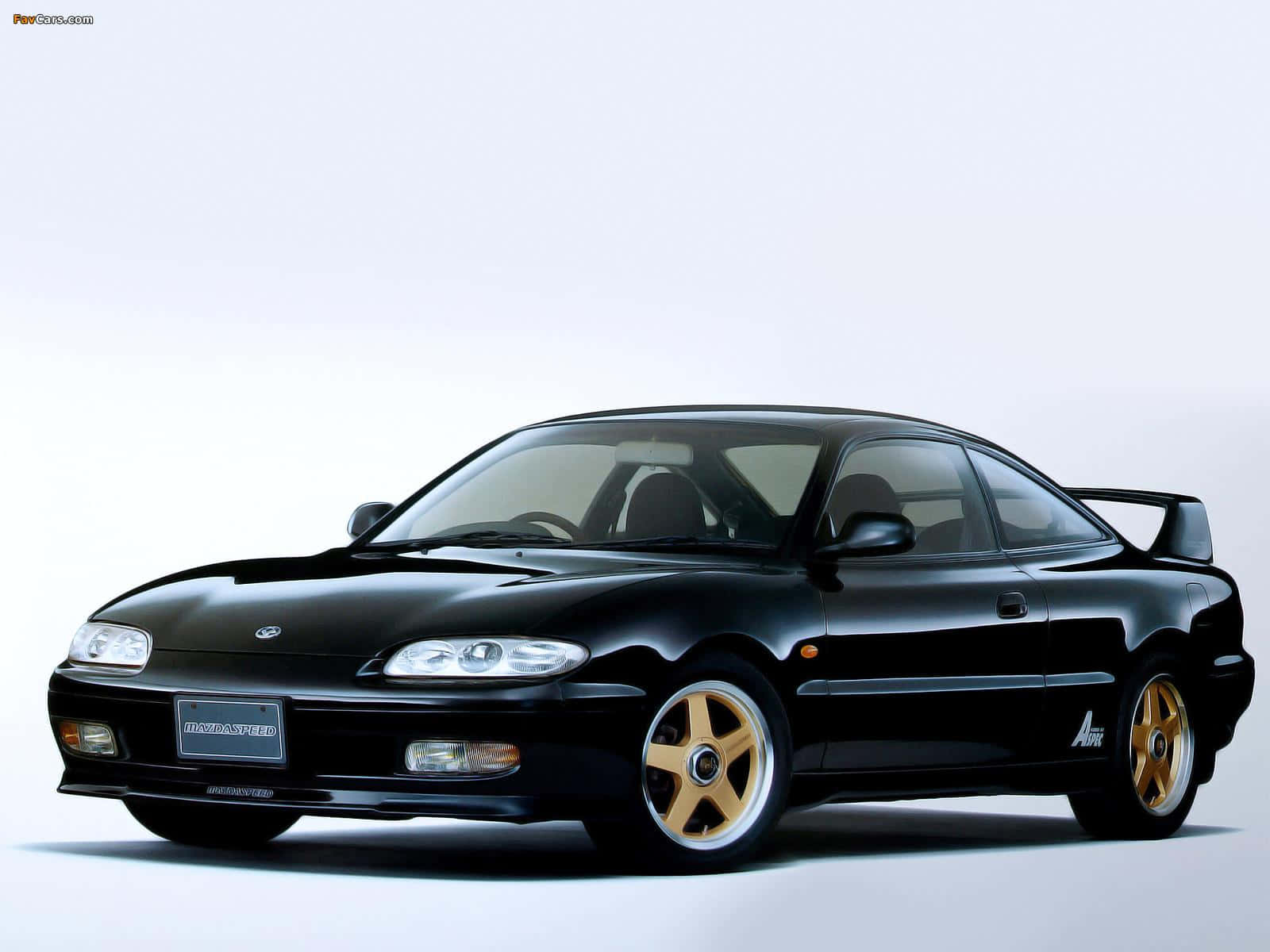 Mazda Mx-6 桌布 壁紙 — 一輛時尚的黑色豐田Celica GT-Four配金色輪圈，在簡約的白色工作室背景前矗立。