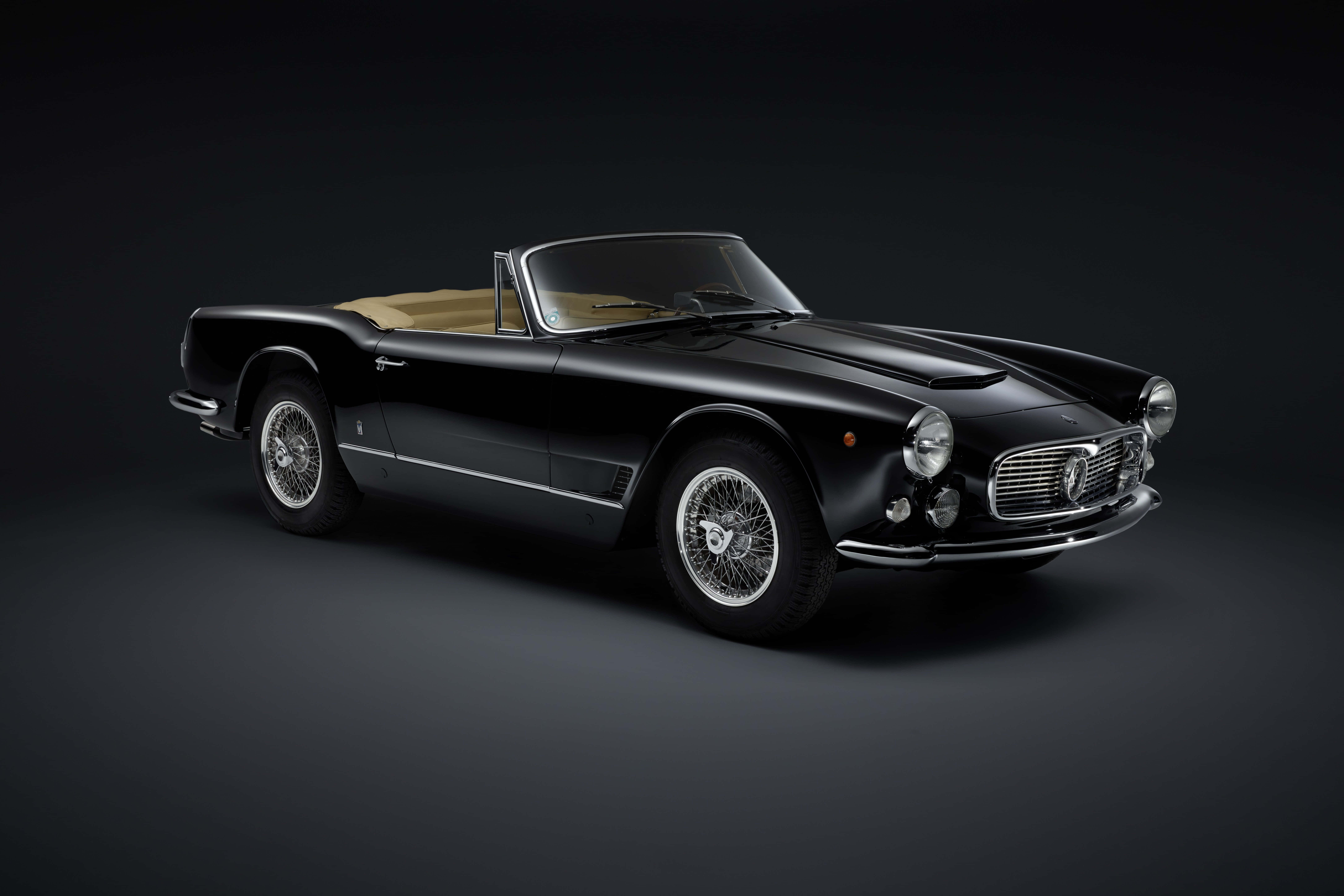 Maserati 3500 Gt 桌布 壁紙 — 一輛時尚的黑色復古法拉利敞篷車，配備米色內飾，在攝影棚燈光下於深色漸變背景中閃耀。