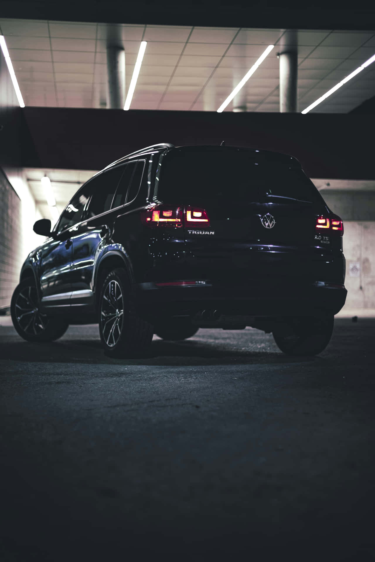  壁紙 — 一輛時尚的黑色福士偉根 Touareg SUV 在昏暗的地下停車場中，在霓虹燈下閃耀。