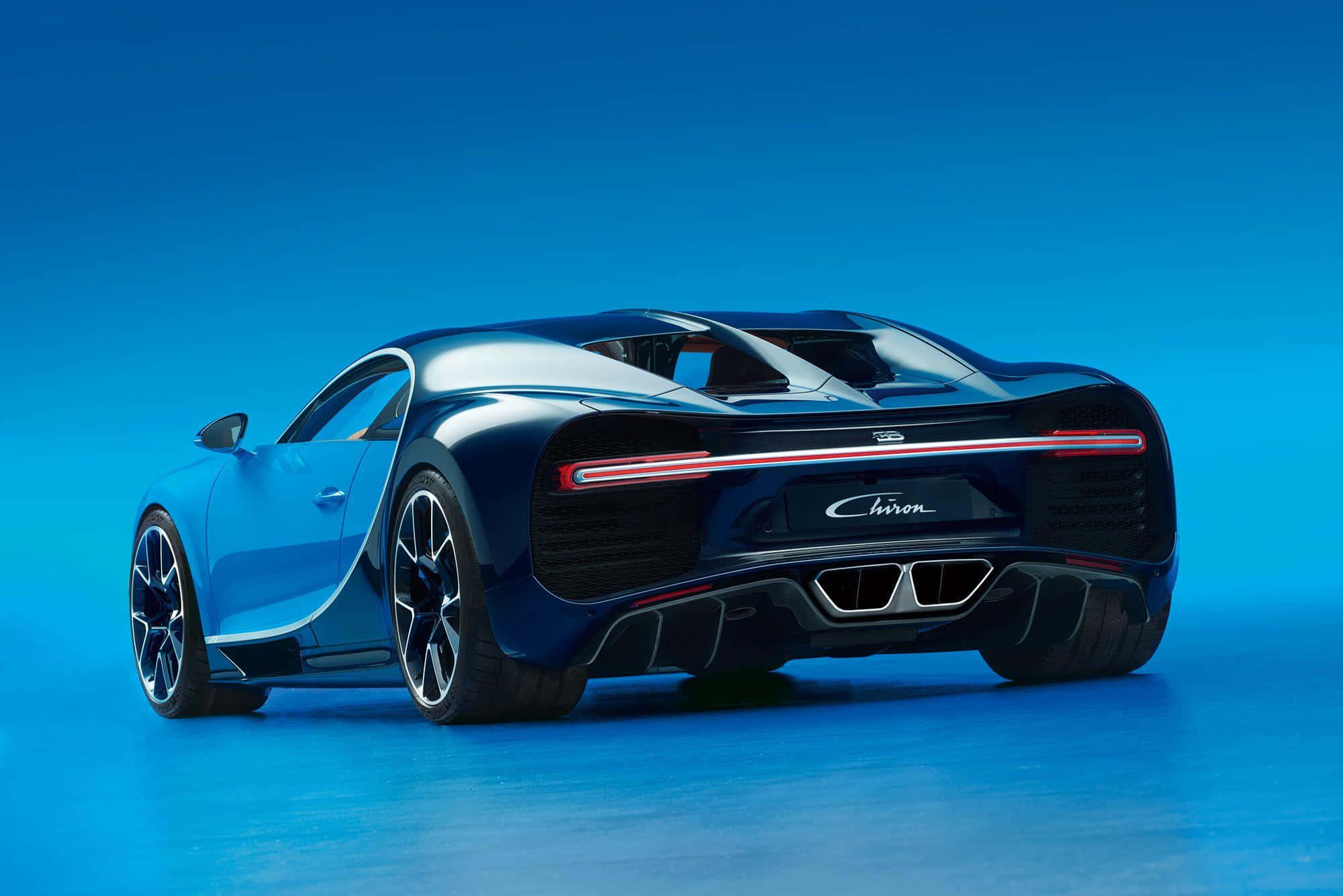 Bugatti Chiron 桌布 壁紙 — 從後方觀看，一輛時尚的藍色 Bugatti Chiron 跑車，背景為純藍色攝影棚背景。