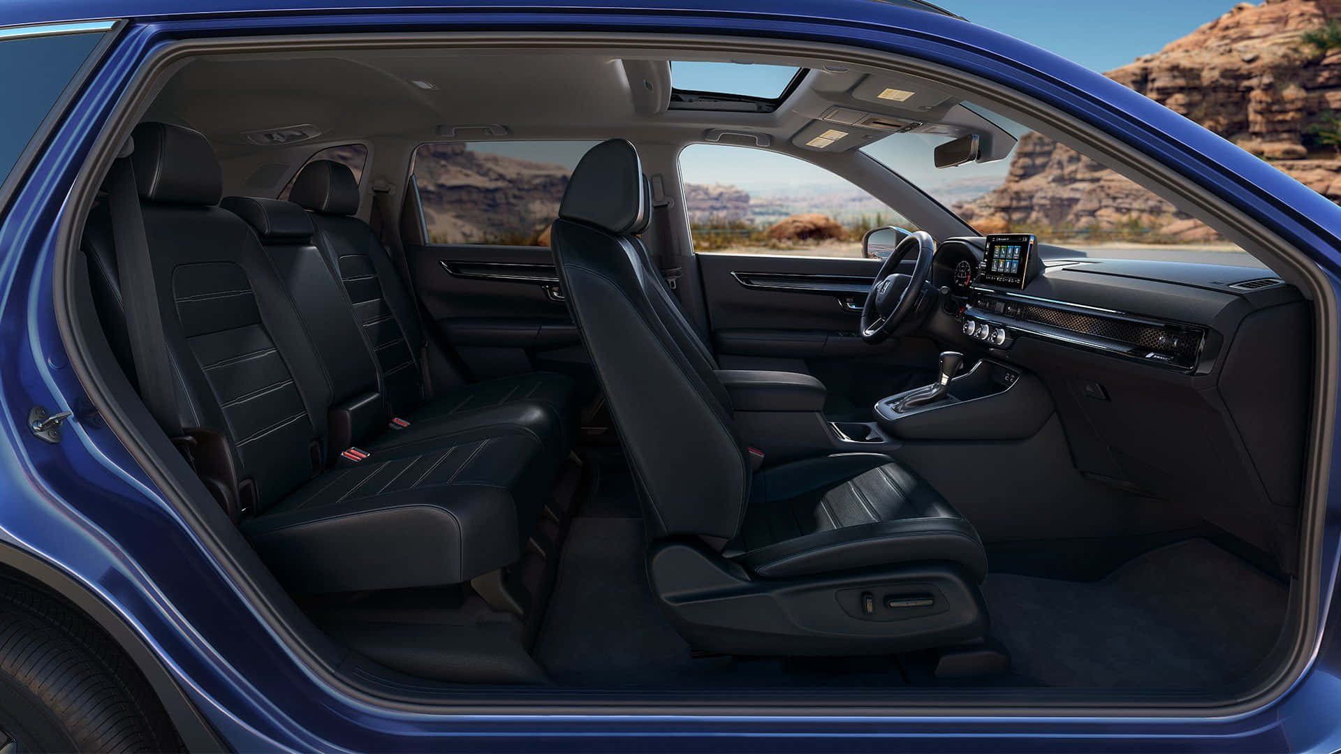 Honda Cr-v 桌布 壁紙 — 一輛時尚藍色汽車敞開的車門，露出豪華黑色皮革內飾，背景是陽光照耀的沙漠岩石地貌。
