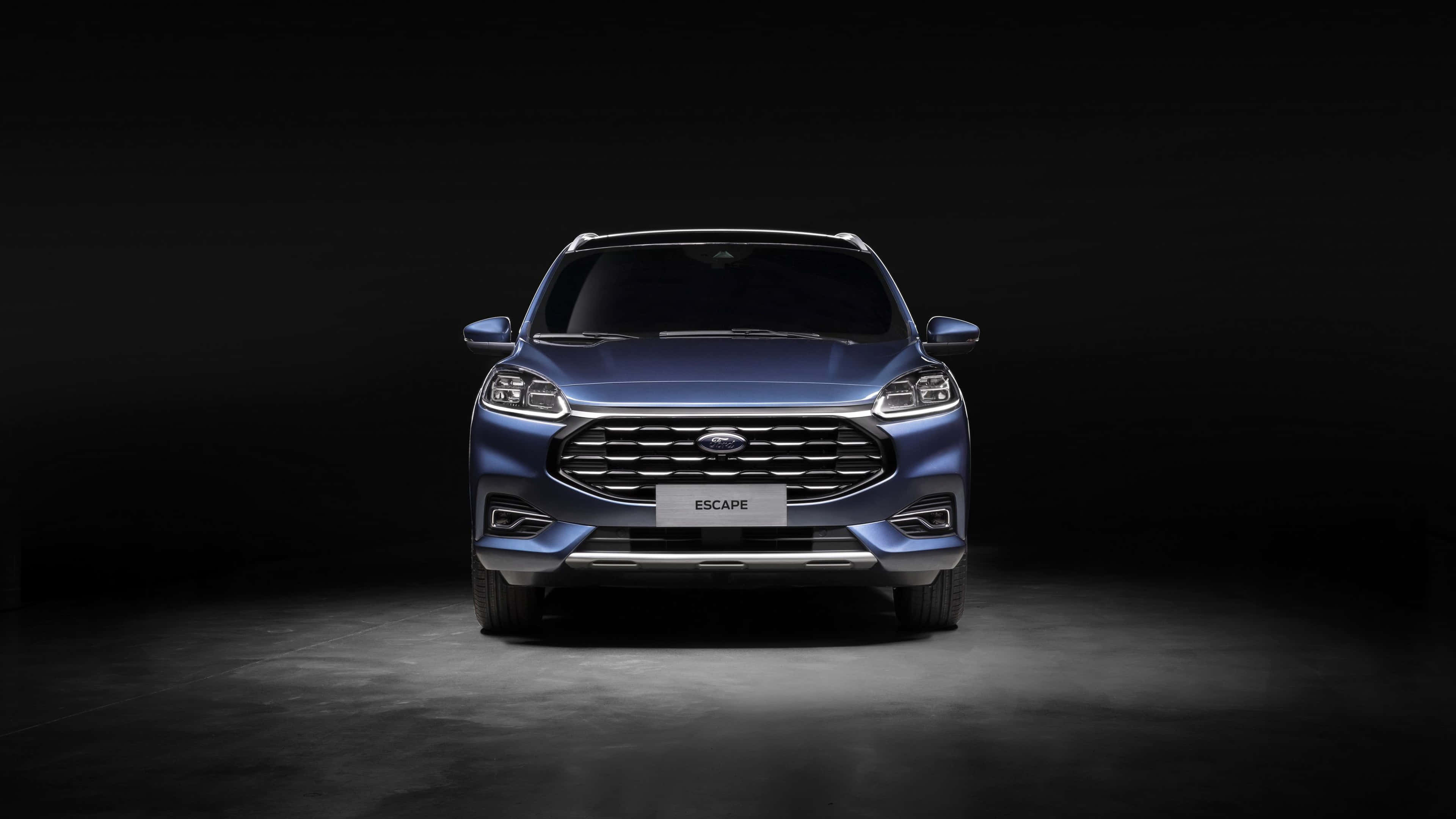 Ford Escape 桌布 壁紙 — 一輛時尚的藍色福特 Escape SUV 在黑暗的攝影棚背景下從下方被戲劇性地照亮。