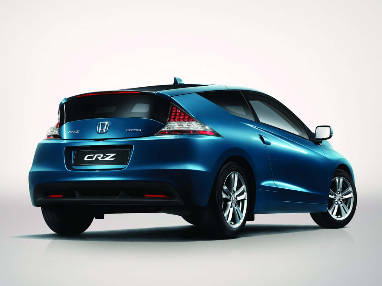 Honda Cr-z 桌布 壁紙 — 一輛時尚的藍色本田 CR-Z 跑車，從後方四分之三角度展示，背景為純白色攝影棚。