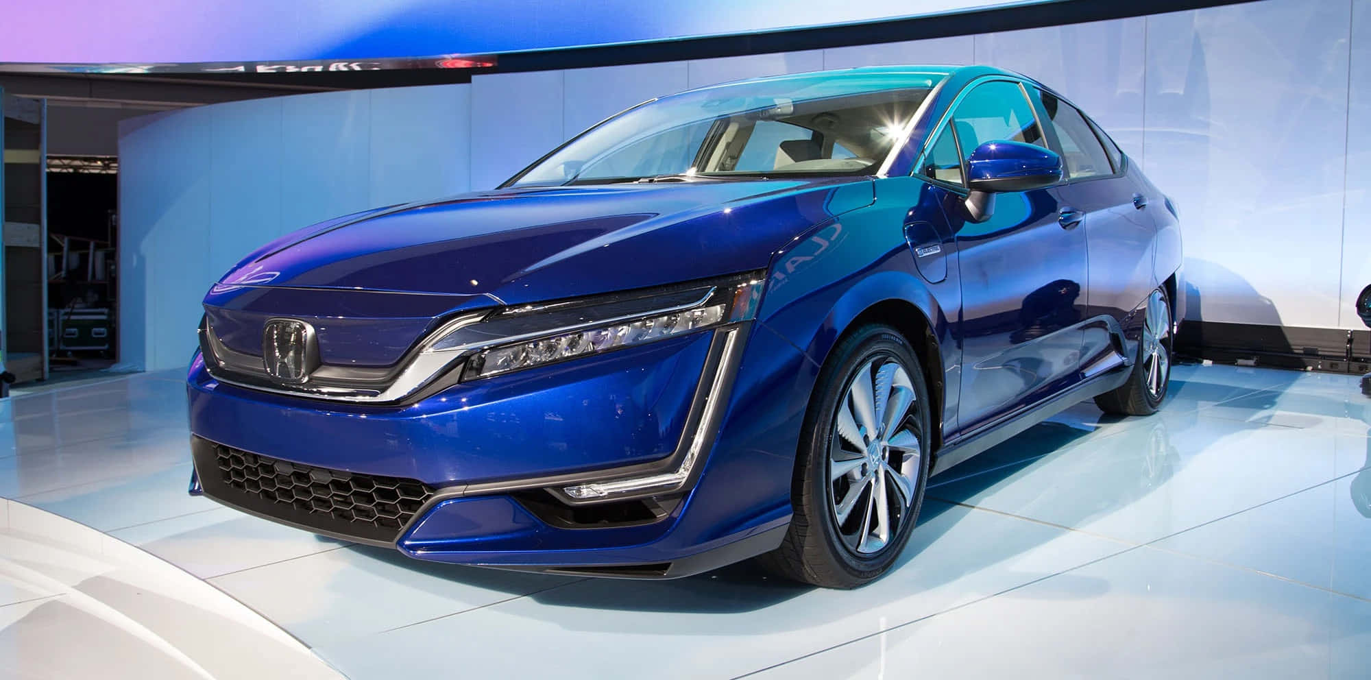 Honda Clarity 桌布 壁紙 — 一輛時尚的藍色本田轎車在白色展廳地板上，在明亮燈光下閃閃發光，地板具有反射表面。